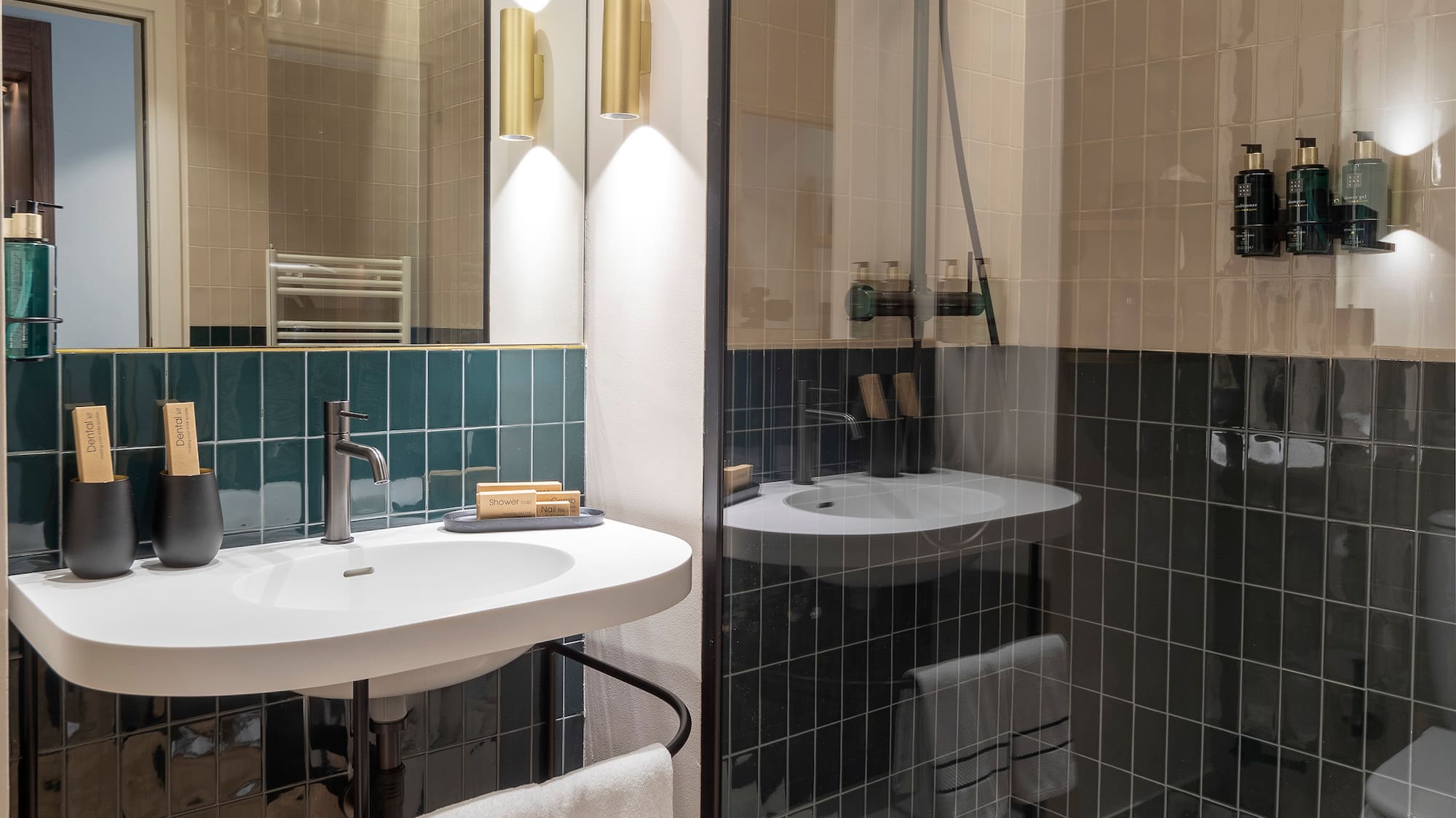 Sleek bathroom with dark green tiles, white vanity, and glass walk-in shower.