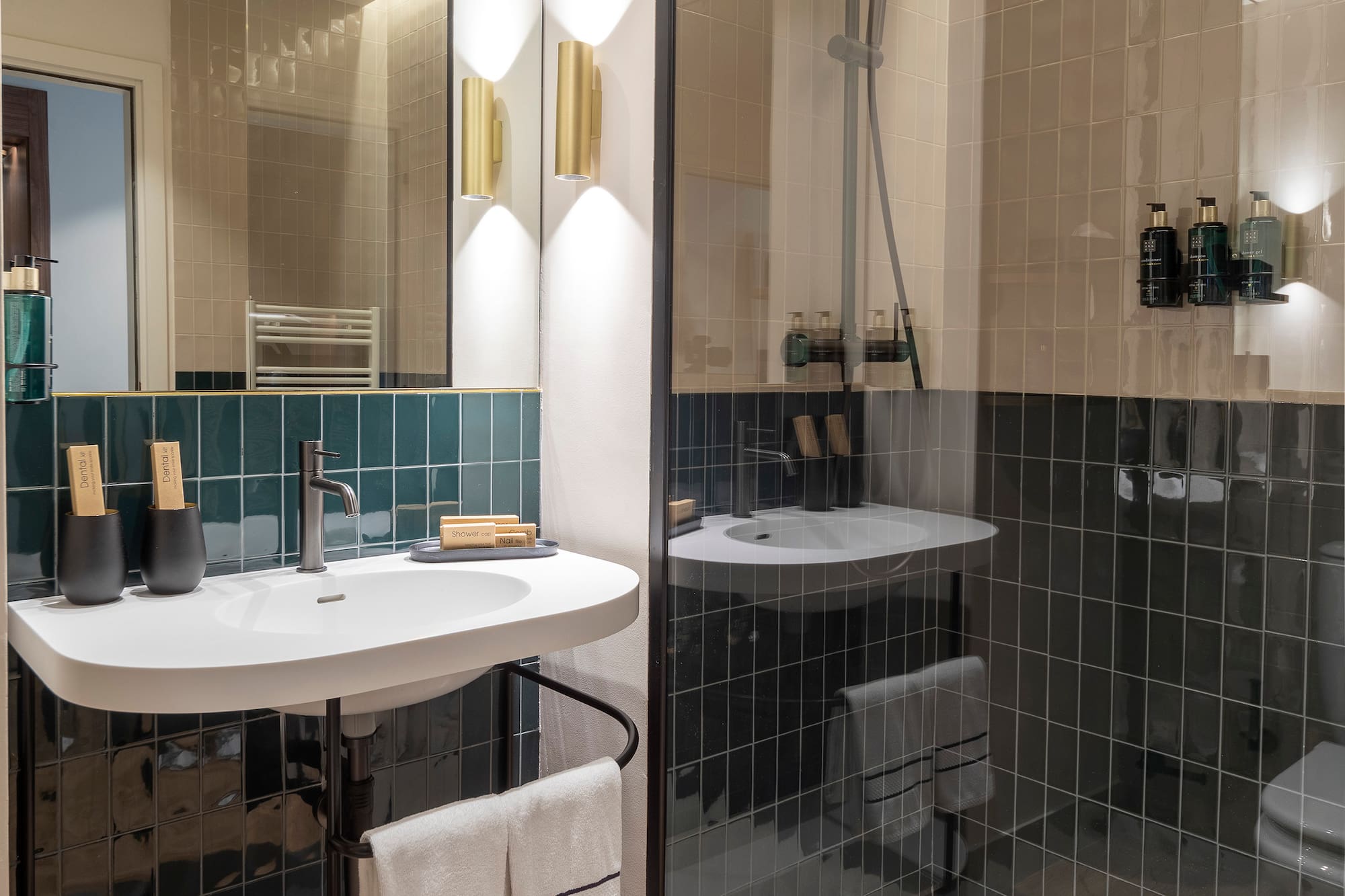 Sleek bathroom with dark green tiles, white vanity, and glass walk-in shower.