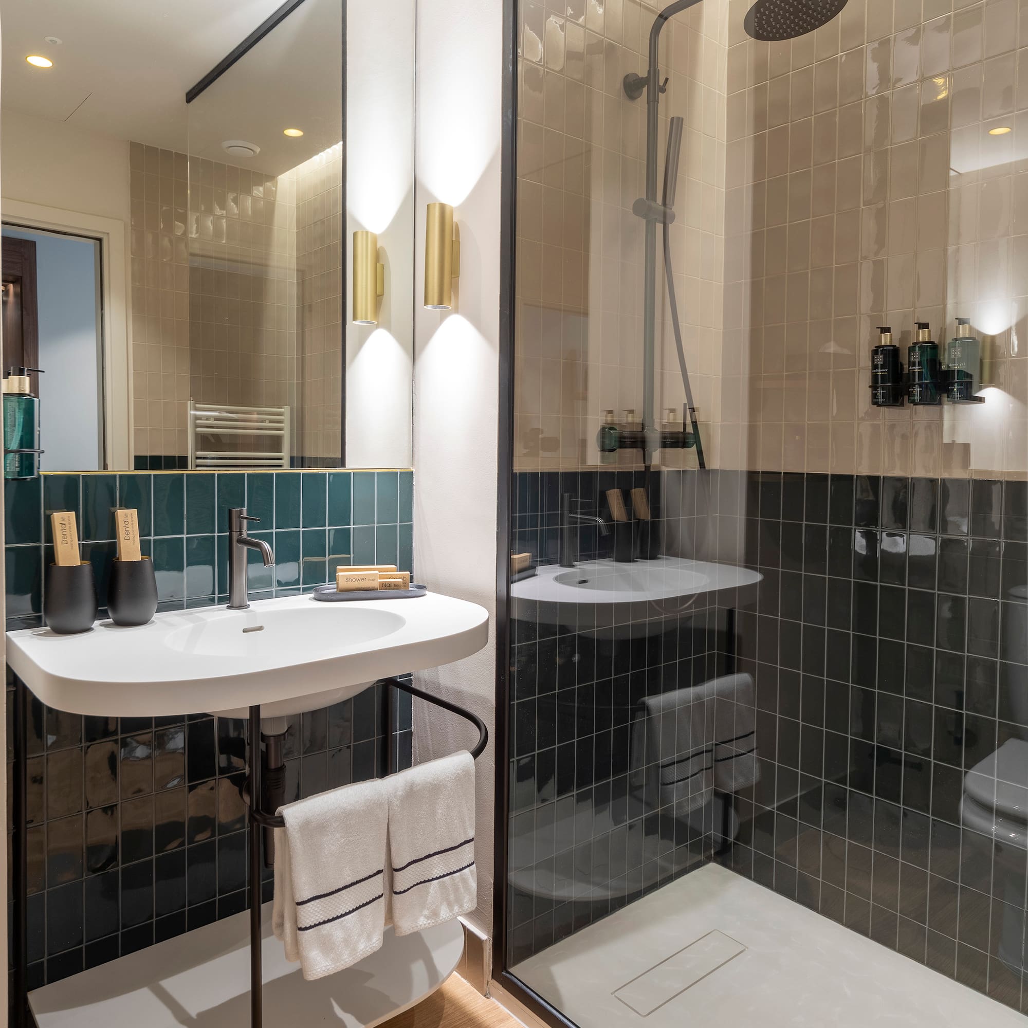 Sleek bathroom with dark green tiles, white vanity, and glass walk-in shower.