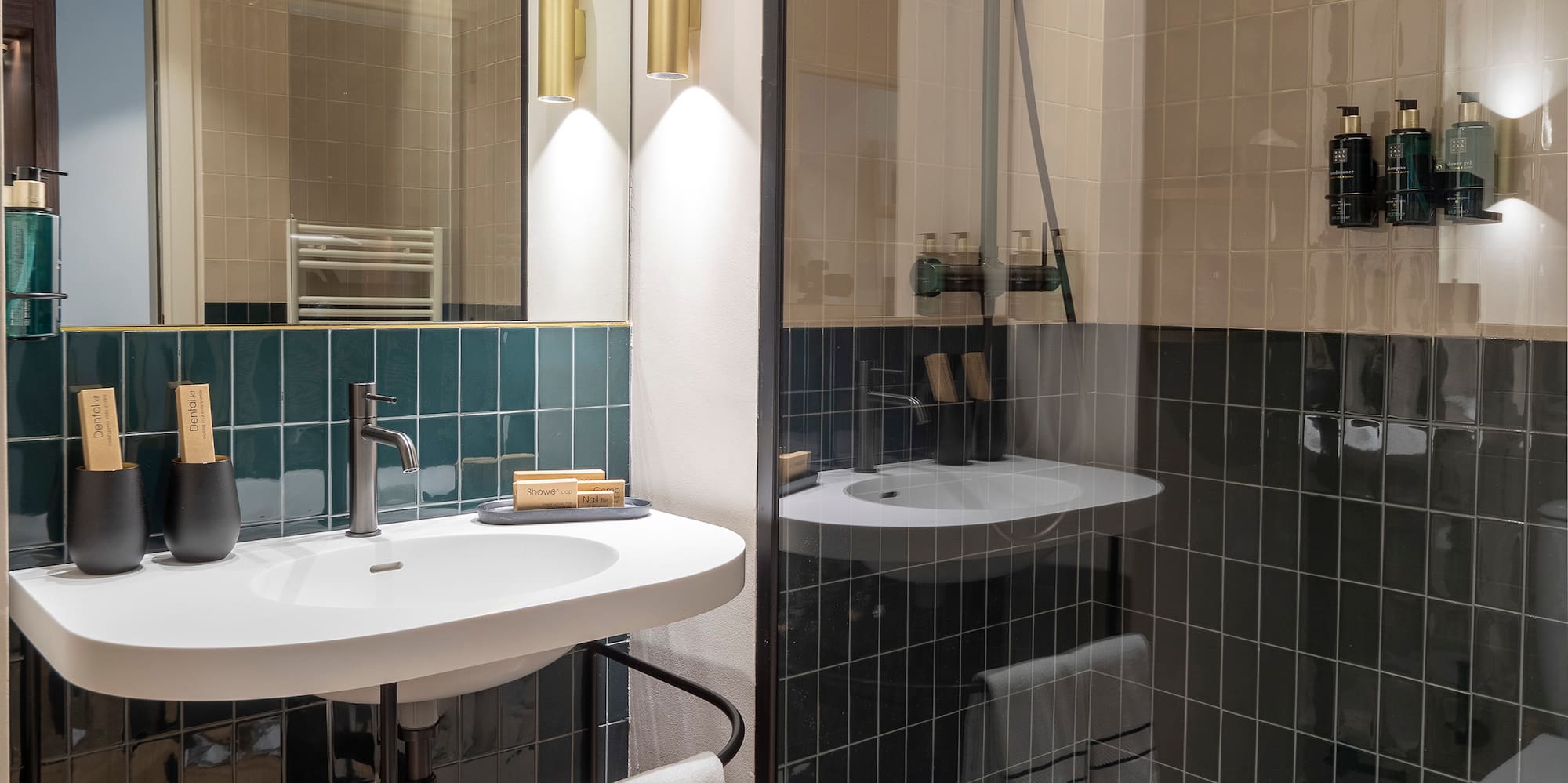 Sleek bathroom with dark green tiles, white vanity, and glass walk-in shower.