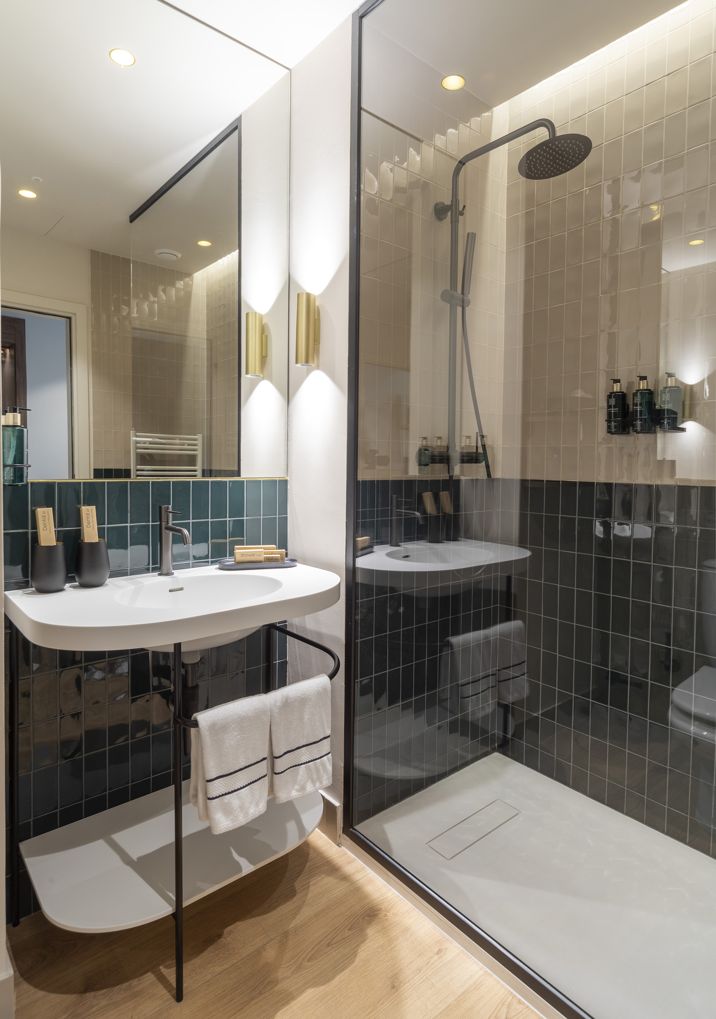 Sleek bathroom with dark green tiles, white vanity, and glass walk-in shower.