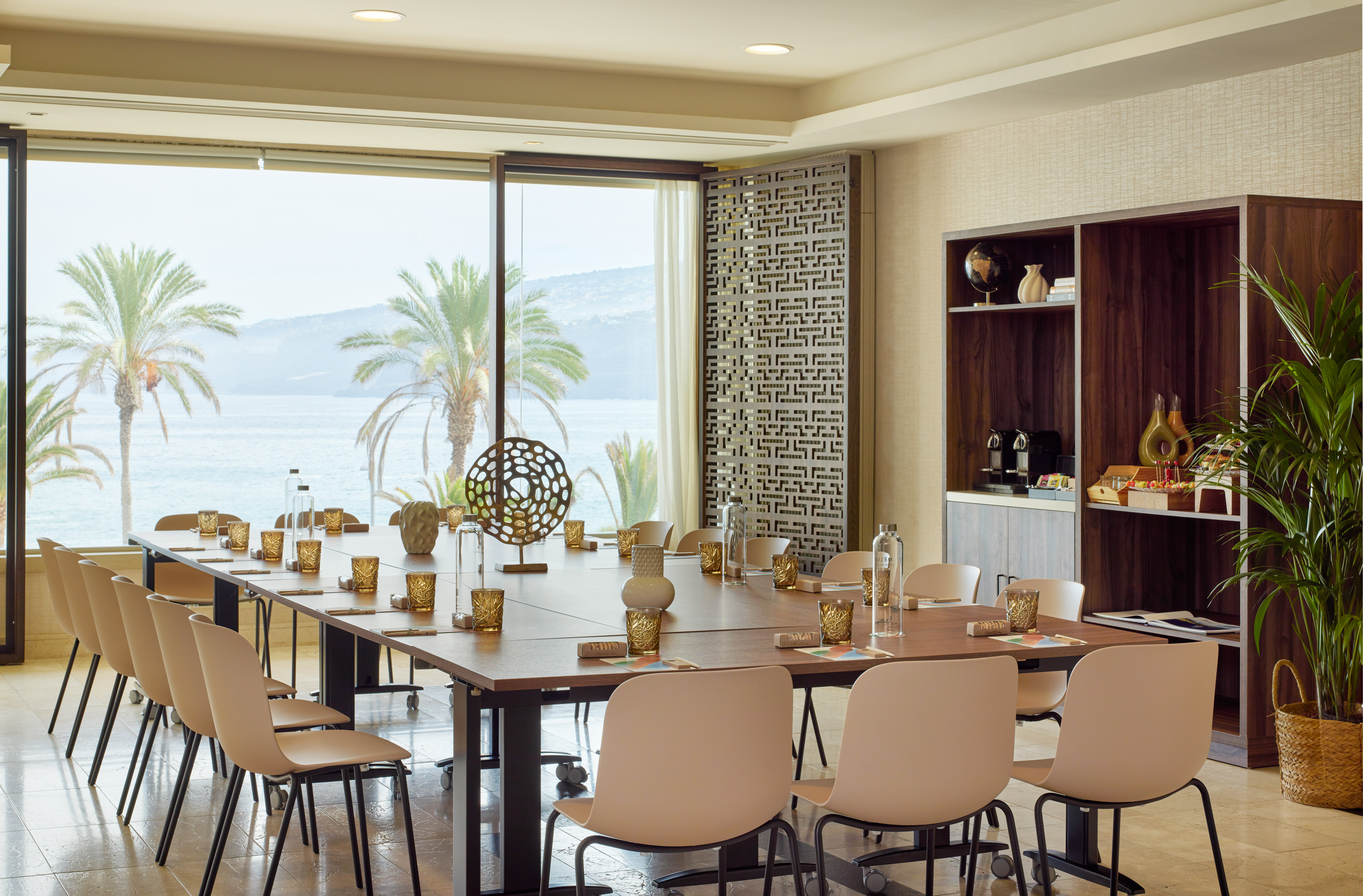 Ocean view conference room with palm trees, large table, and professional setup.
