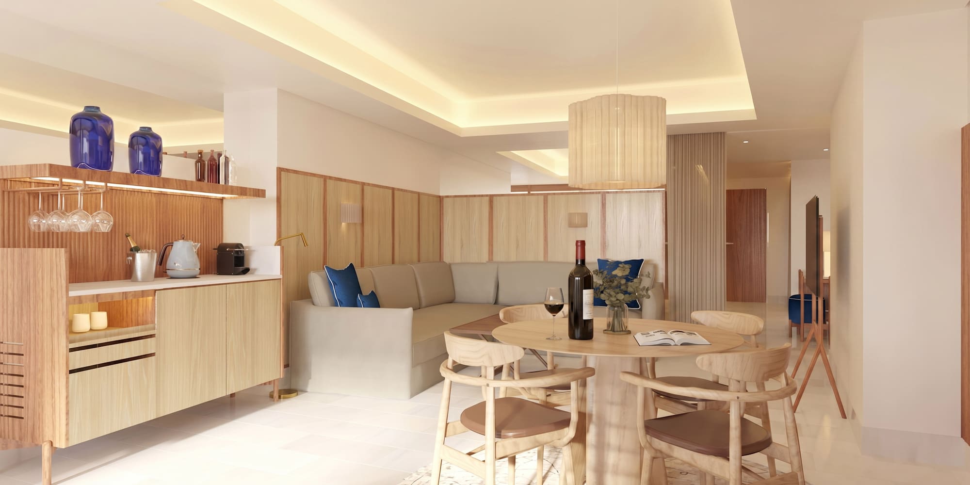 Modern hotel suite living room with dining table, sofa, and kitchenette.