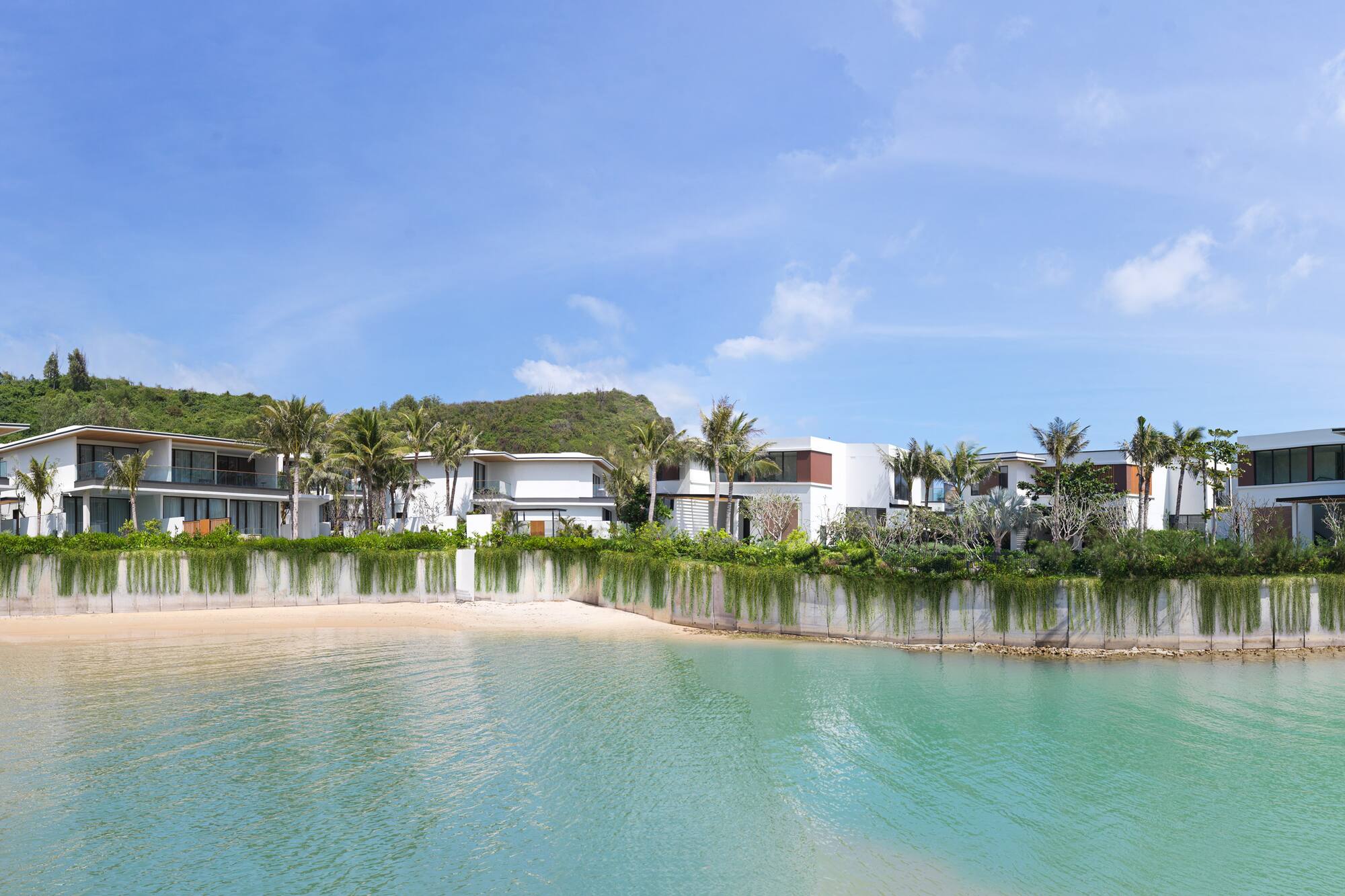 Modern luxury villas on a tropical beach with clear turquoise ocean.