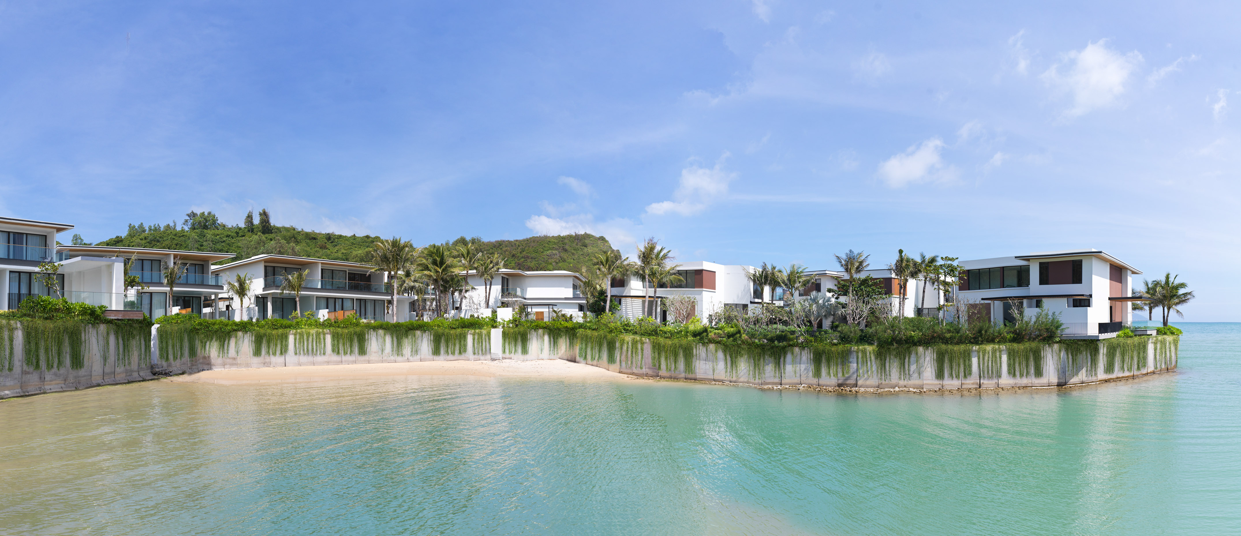 Modern luxury villas on a tropical beach with clear turquoise ocean.