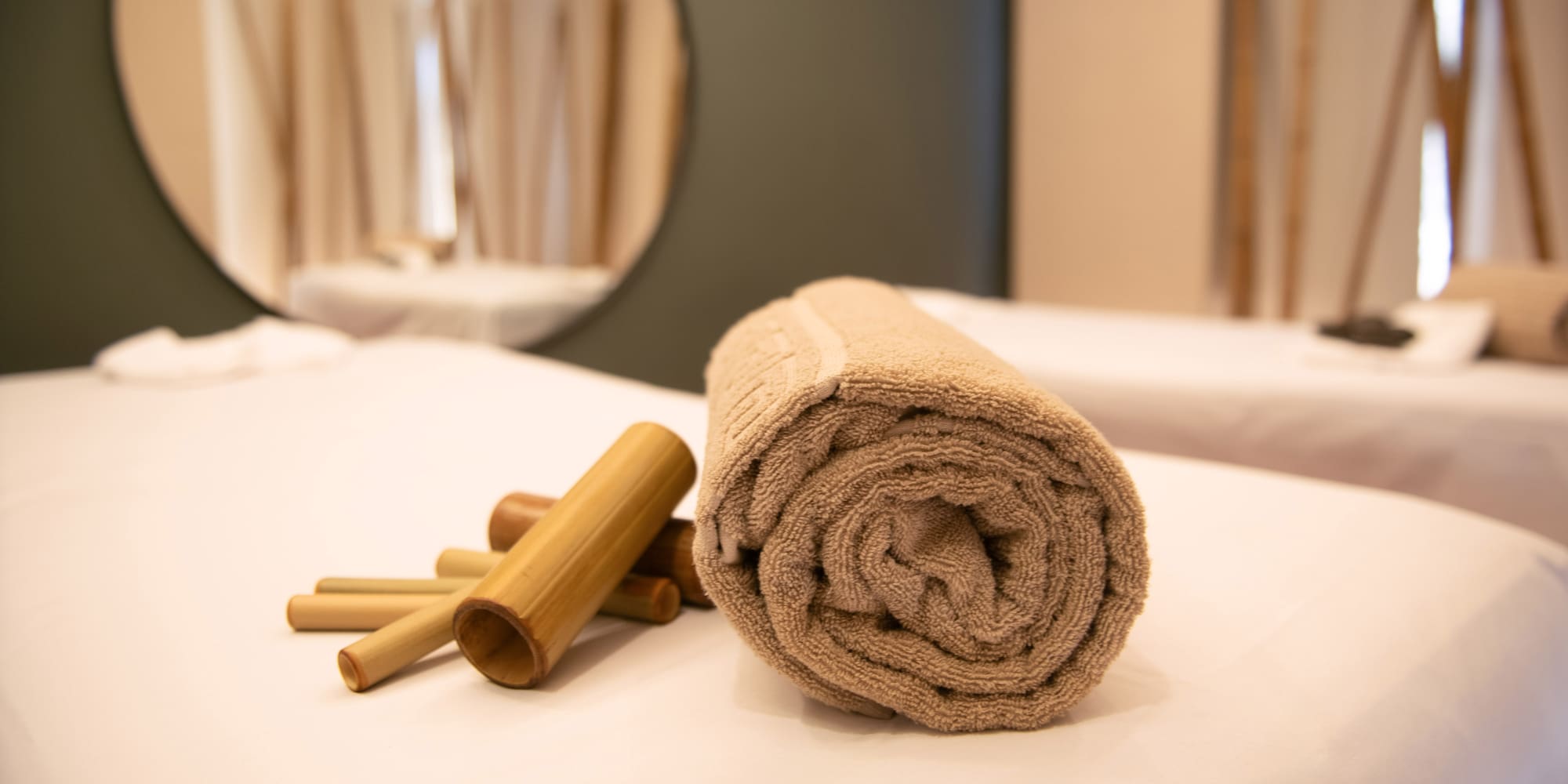 a rolled up towel and bamboo sticks on a bed