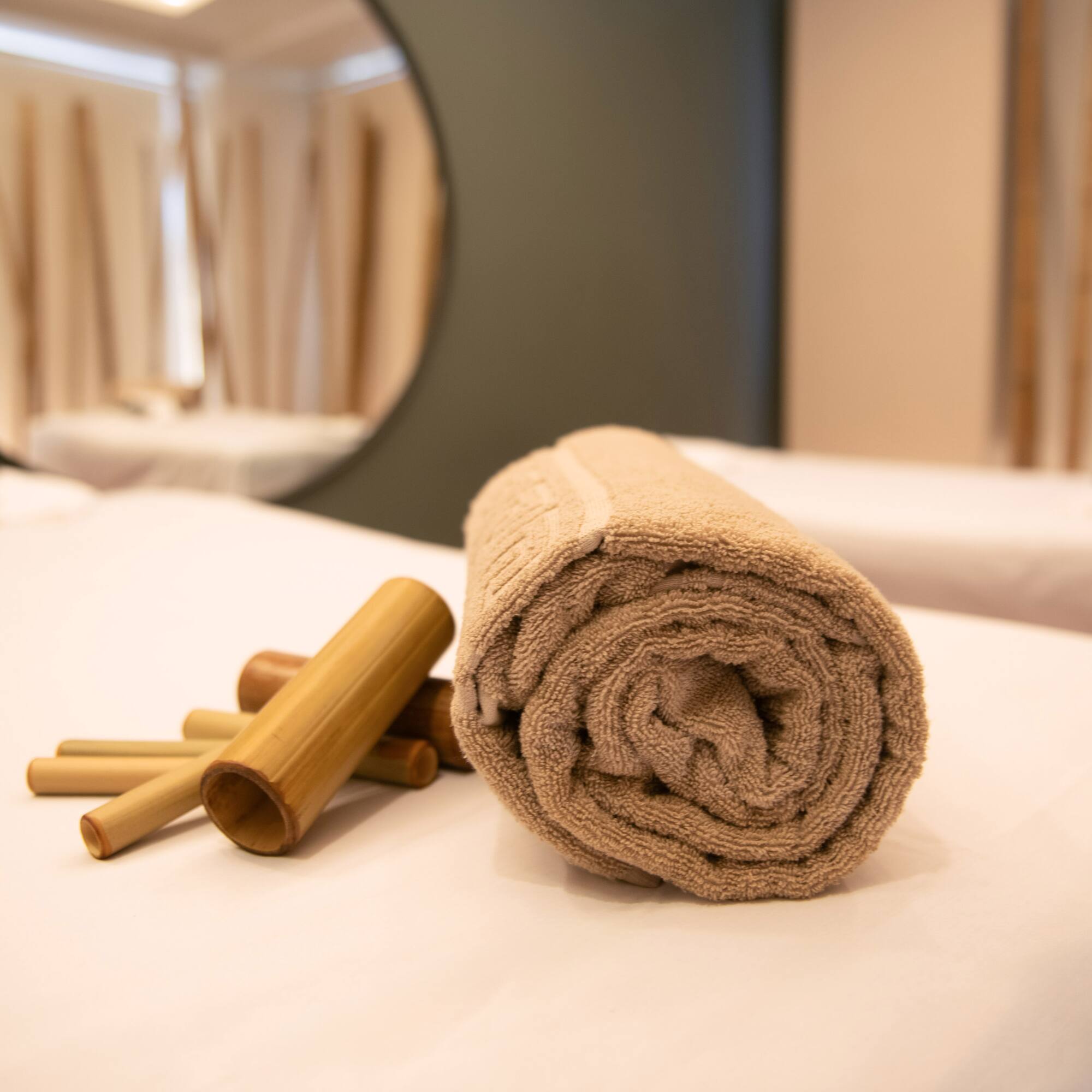 a rolled up towel and bamboo sticks on a bed