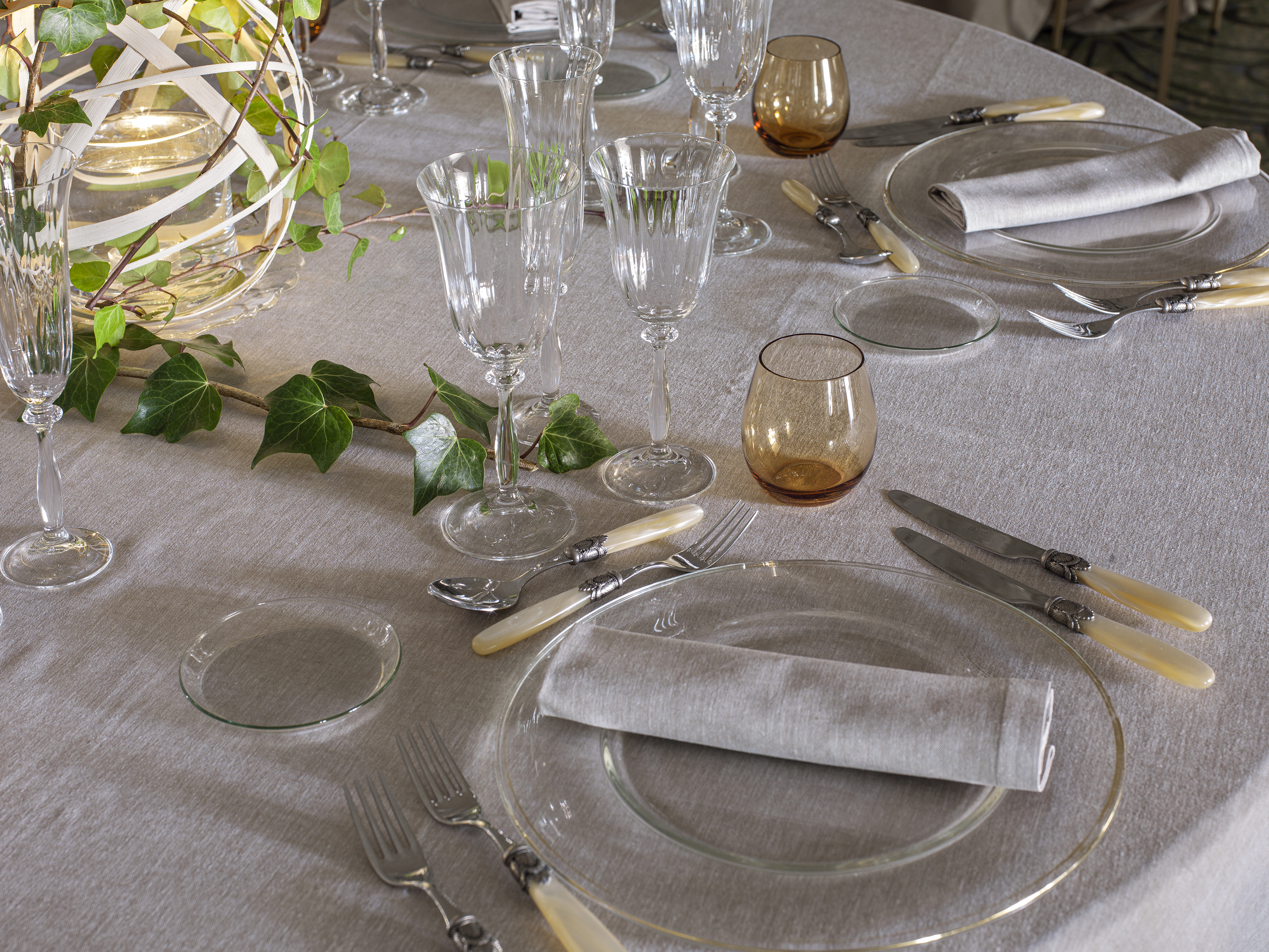 Elegant dinner table setting with crystal glasses, ivory cutlery, and ivy decor.