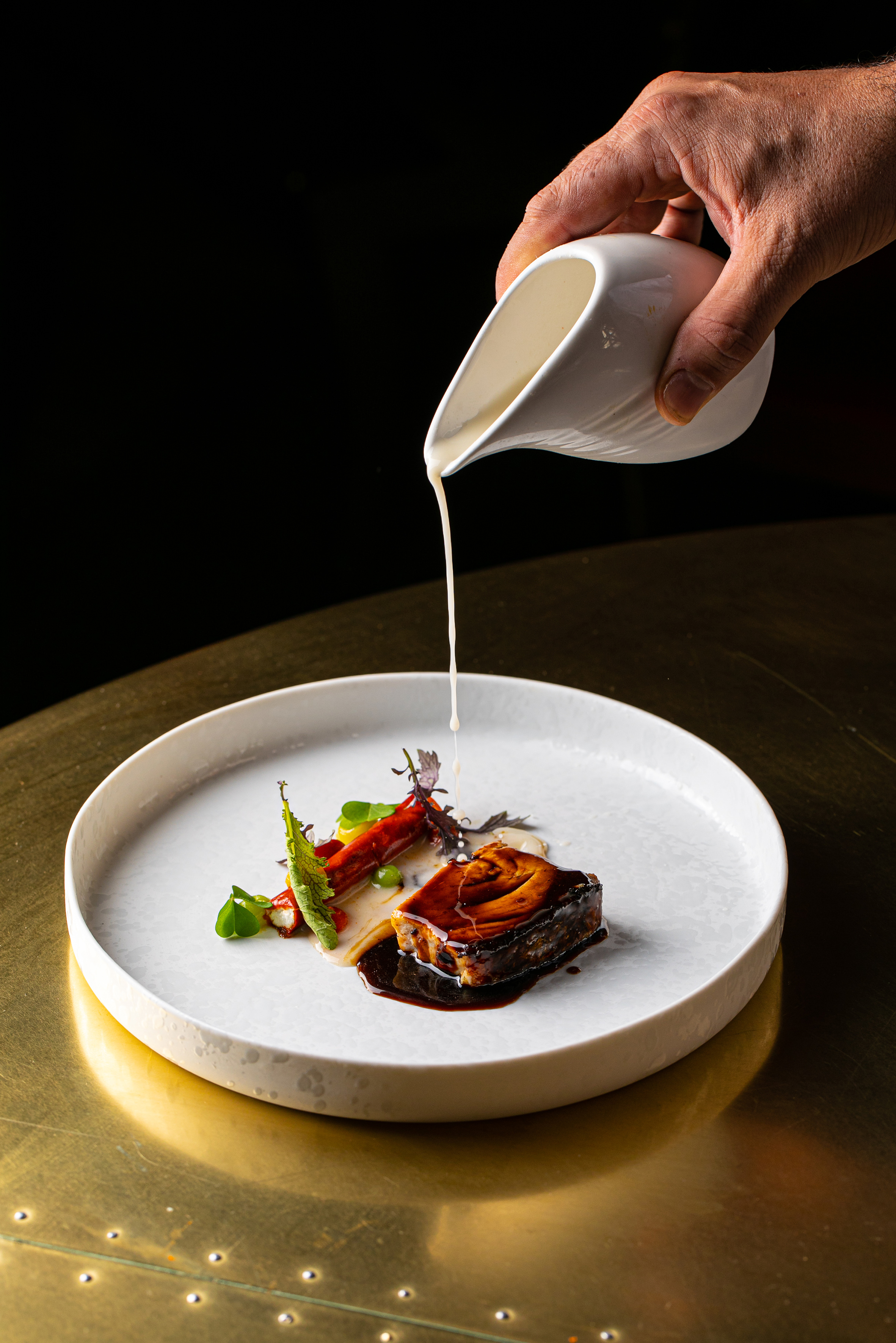a hand pouring milk onto a plate of food