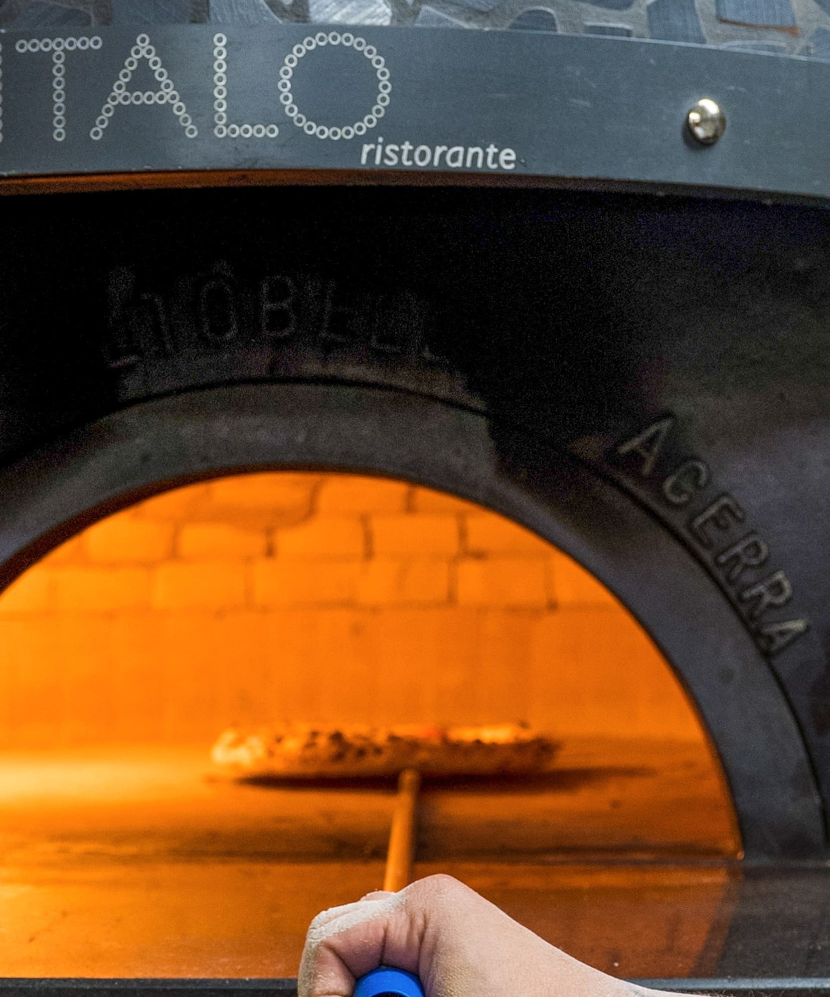 a hand holding a blue pen in a pizza oven