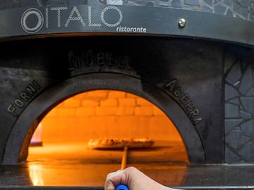 a hand holding a blue pen in a pizza oven