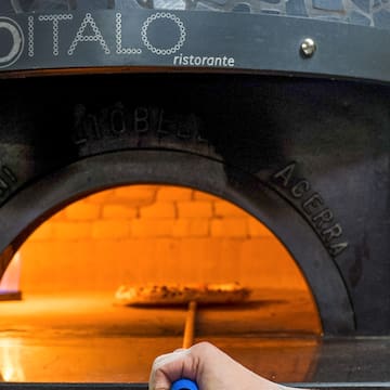 a hand holding a blue pen in a pizza oven