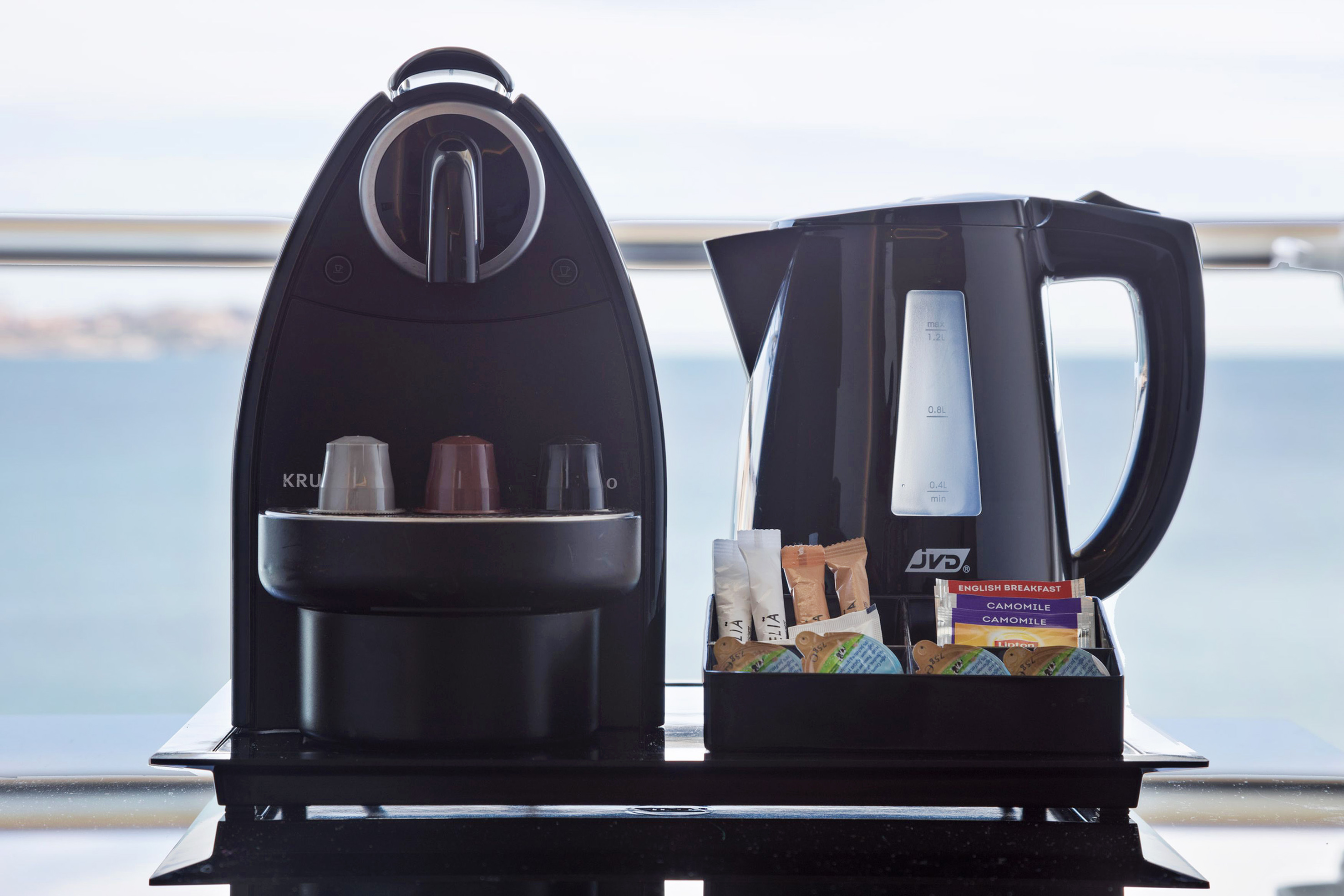 In-room coffee machine, electric kettle, tea, and coffee pods with sea view.