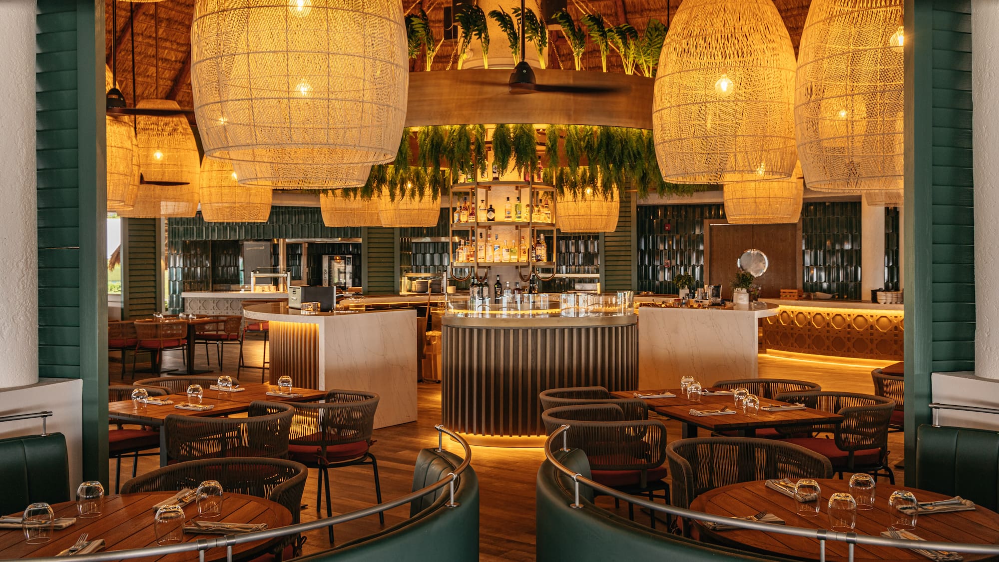 Tropical resort restaurant bar with large woven pendant lights and central circular bar.