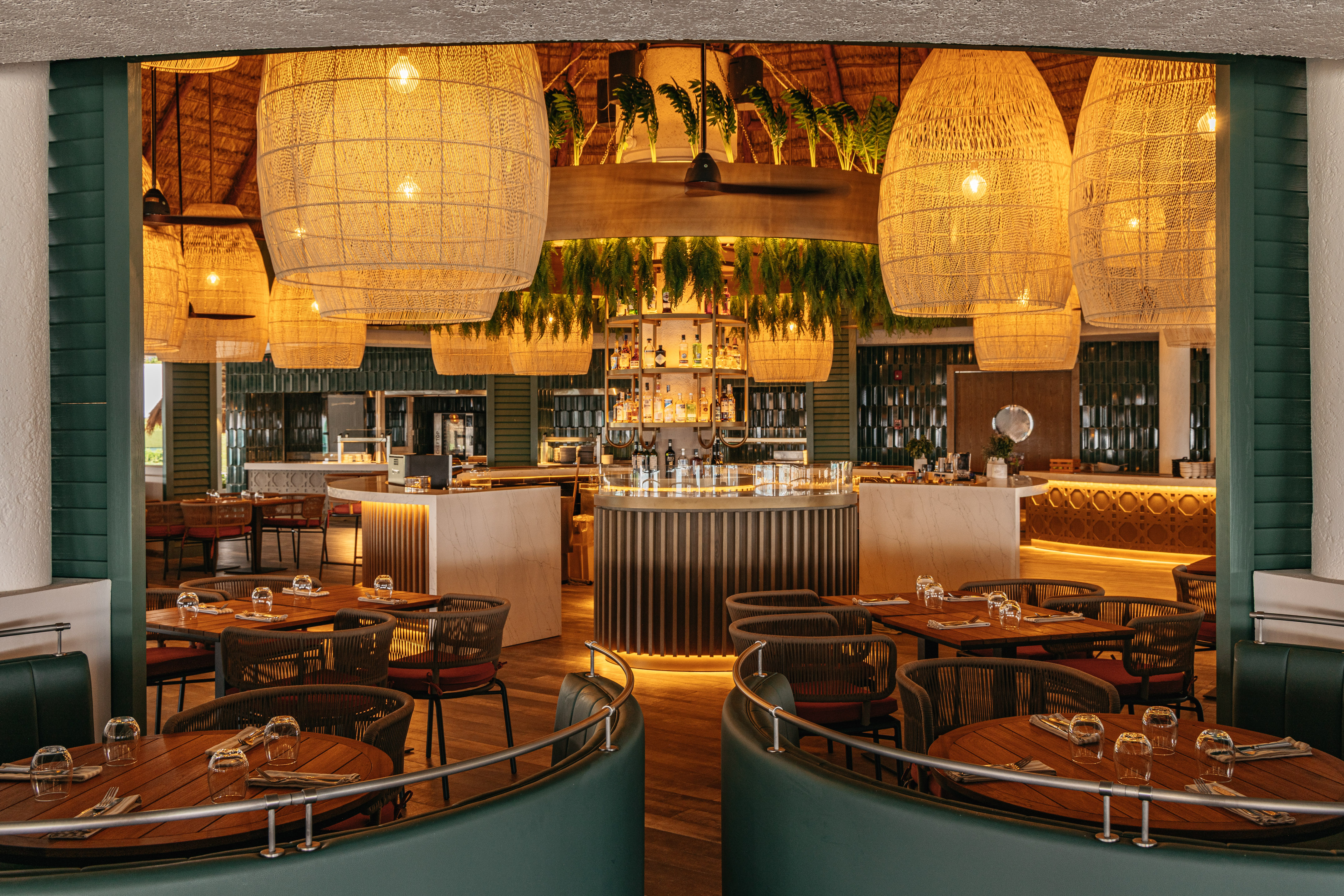 Tropical resort restaurant bar with large woven pendant lights and central circular bar.