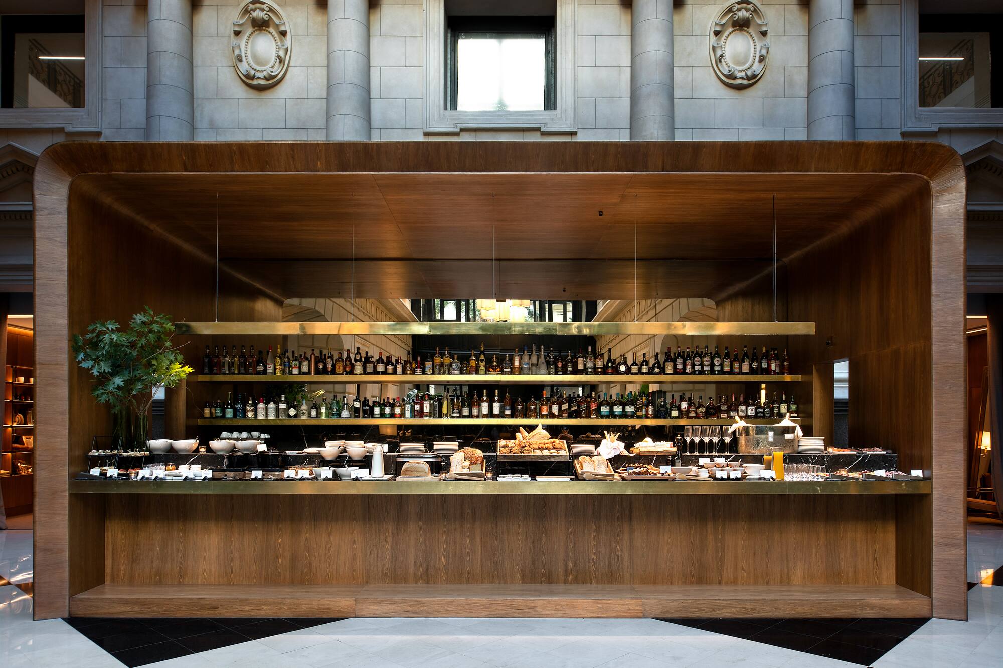 Luxurious hotel buffet bar counter with spirits, pastries, and food items.