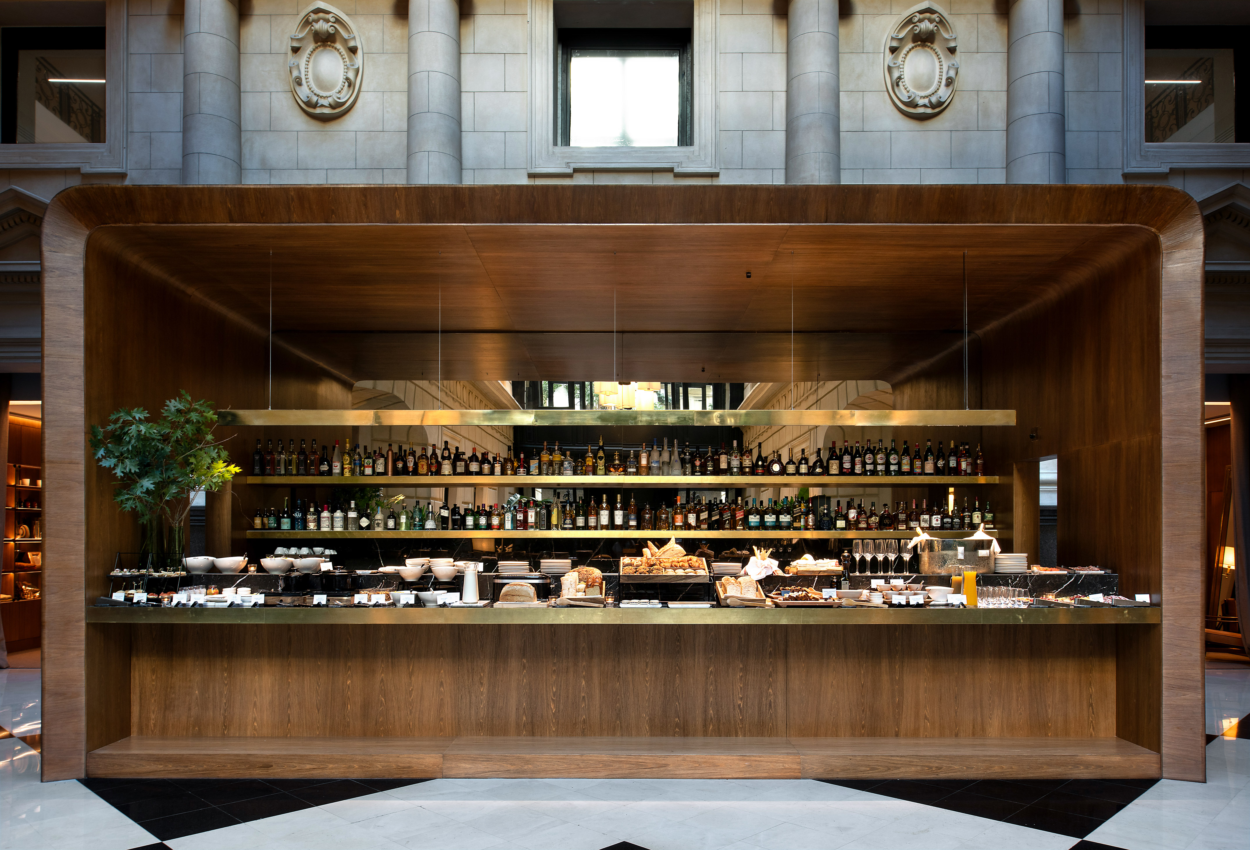 Luxurious hotel buffet bar counter with spirits, pastries, and food items.