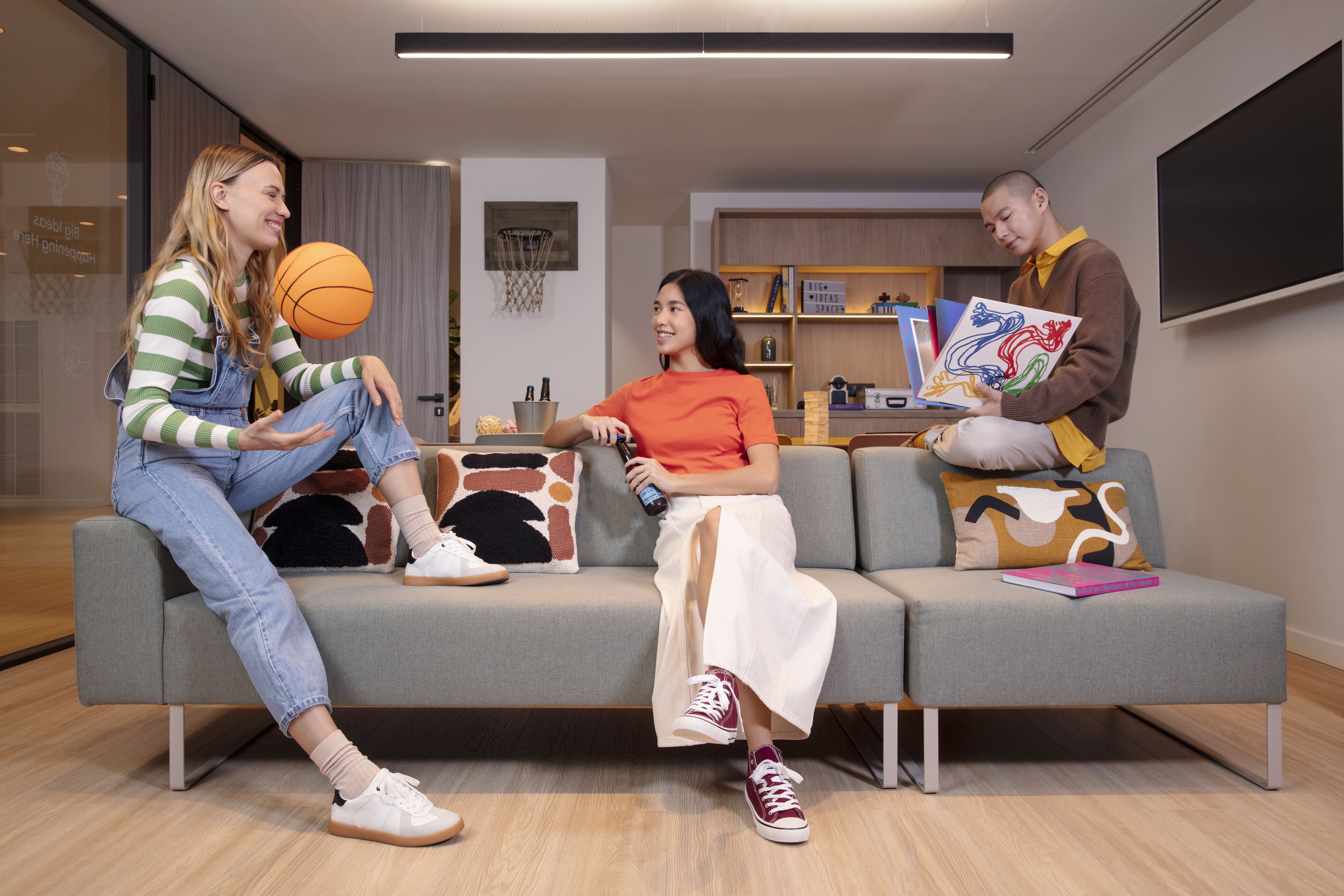 Young team relaxing in a modern office lounge with basketball and art.