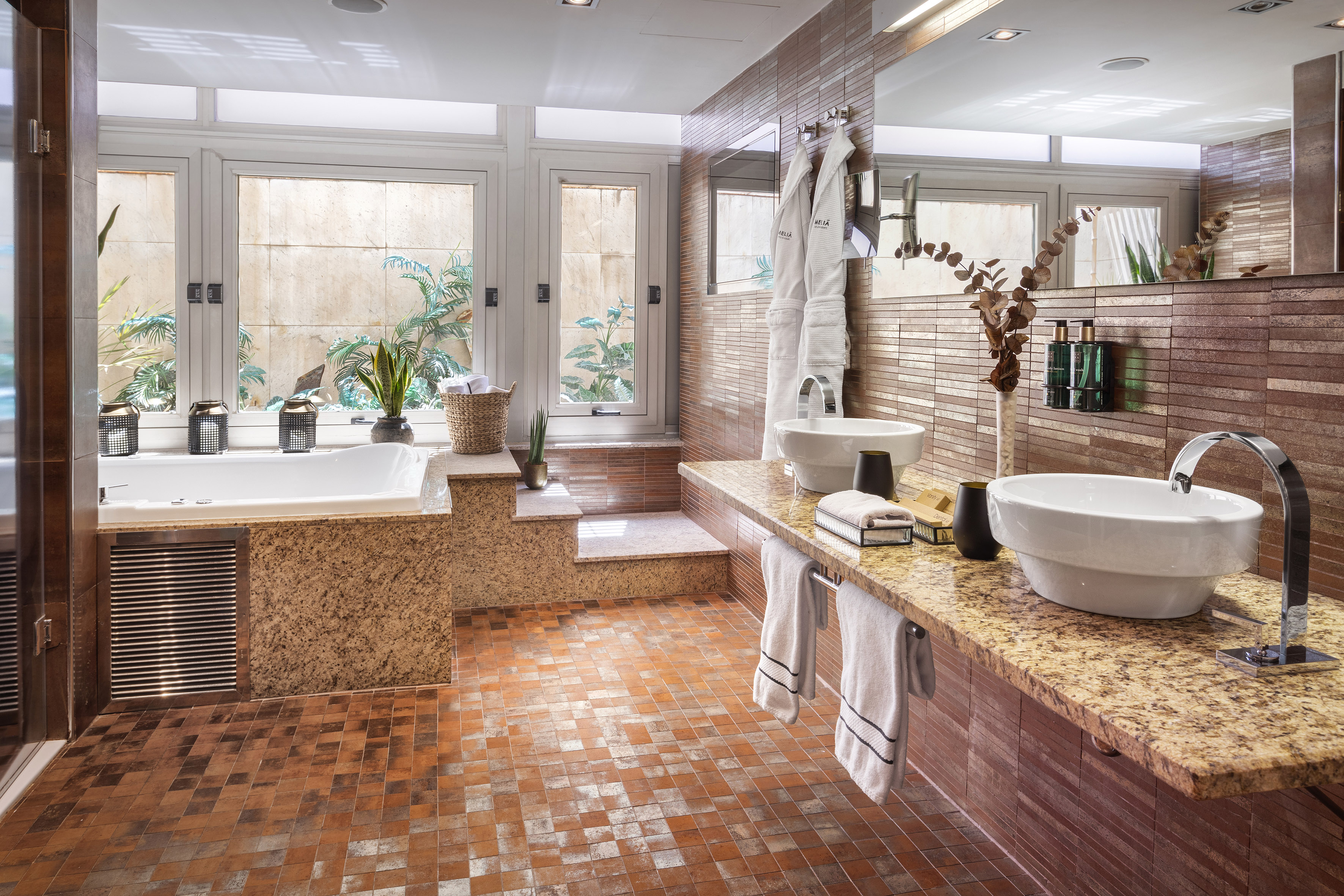 Hotel luxury bathroom with garden view tub, dual sinks, and granite counter.