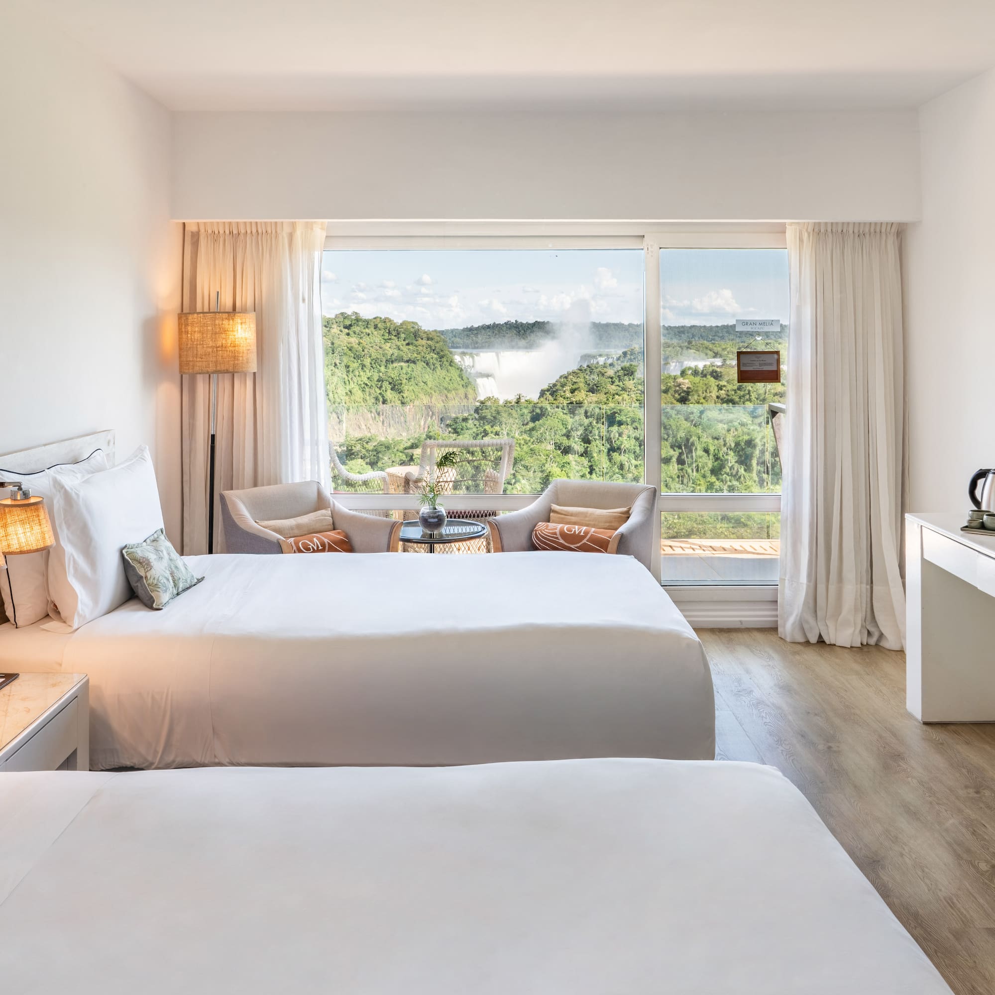 a room with two beds and a table with a view of the mountains