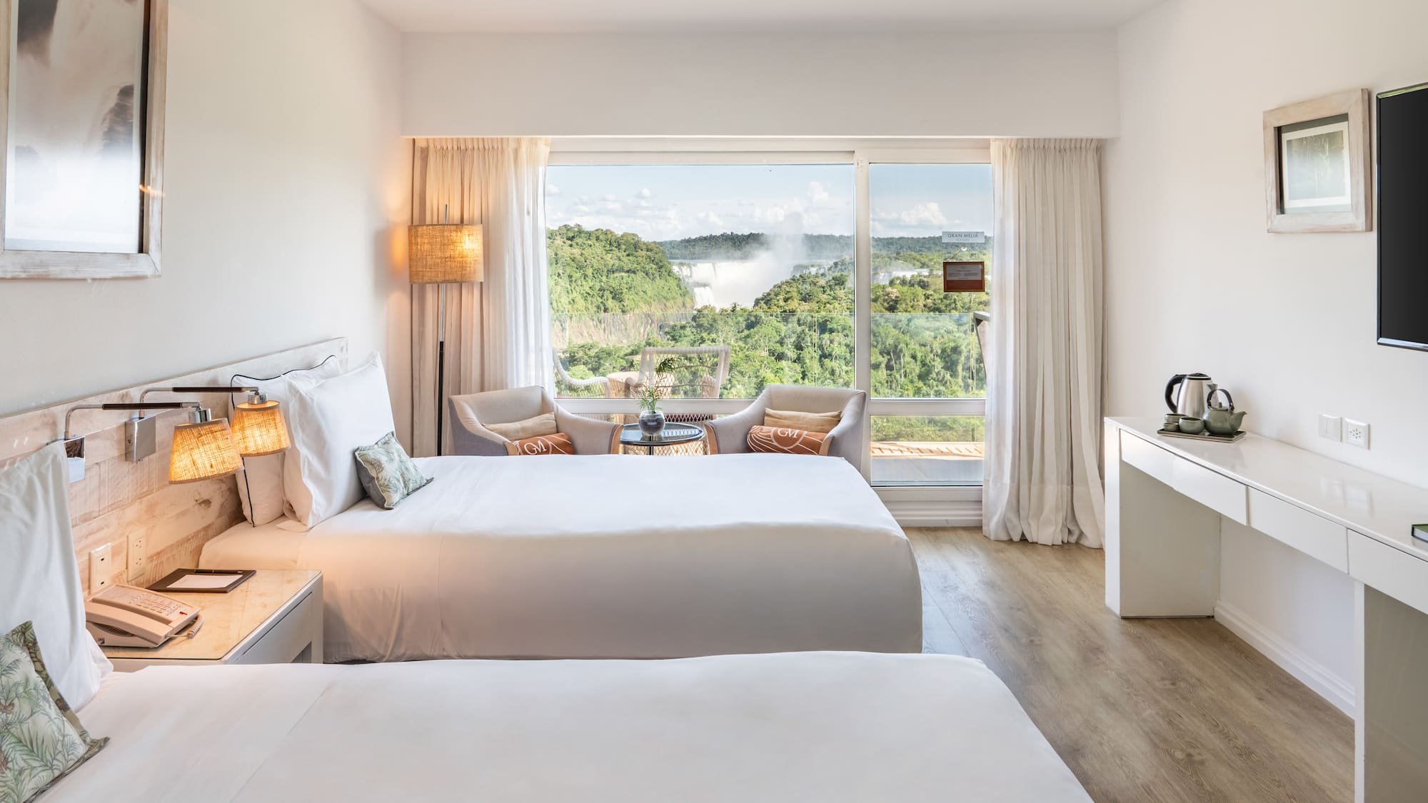 a room with two beds and a table with a view of the mountains