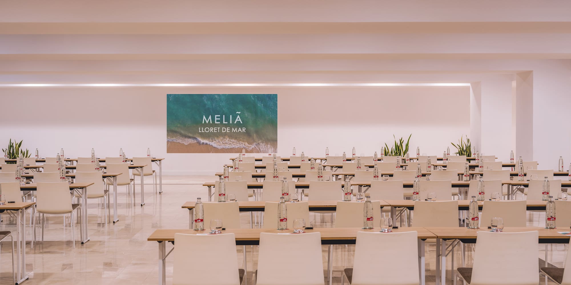 Meliã Lloret de Mar conference room with rows of tables, chairs, and screen.