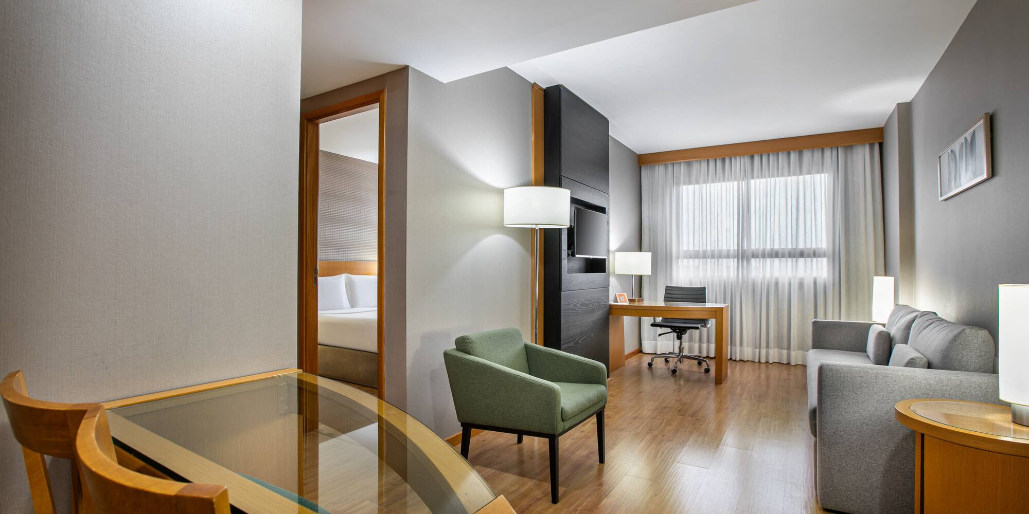 Contemporary hotel suite with separate living and sleeping areas.