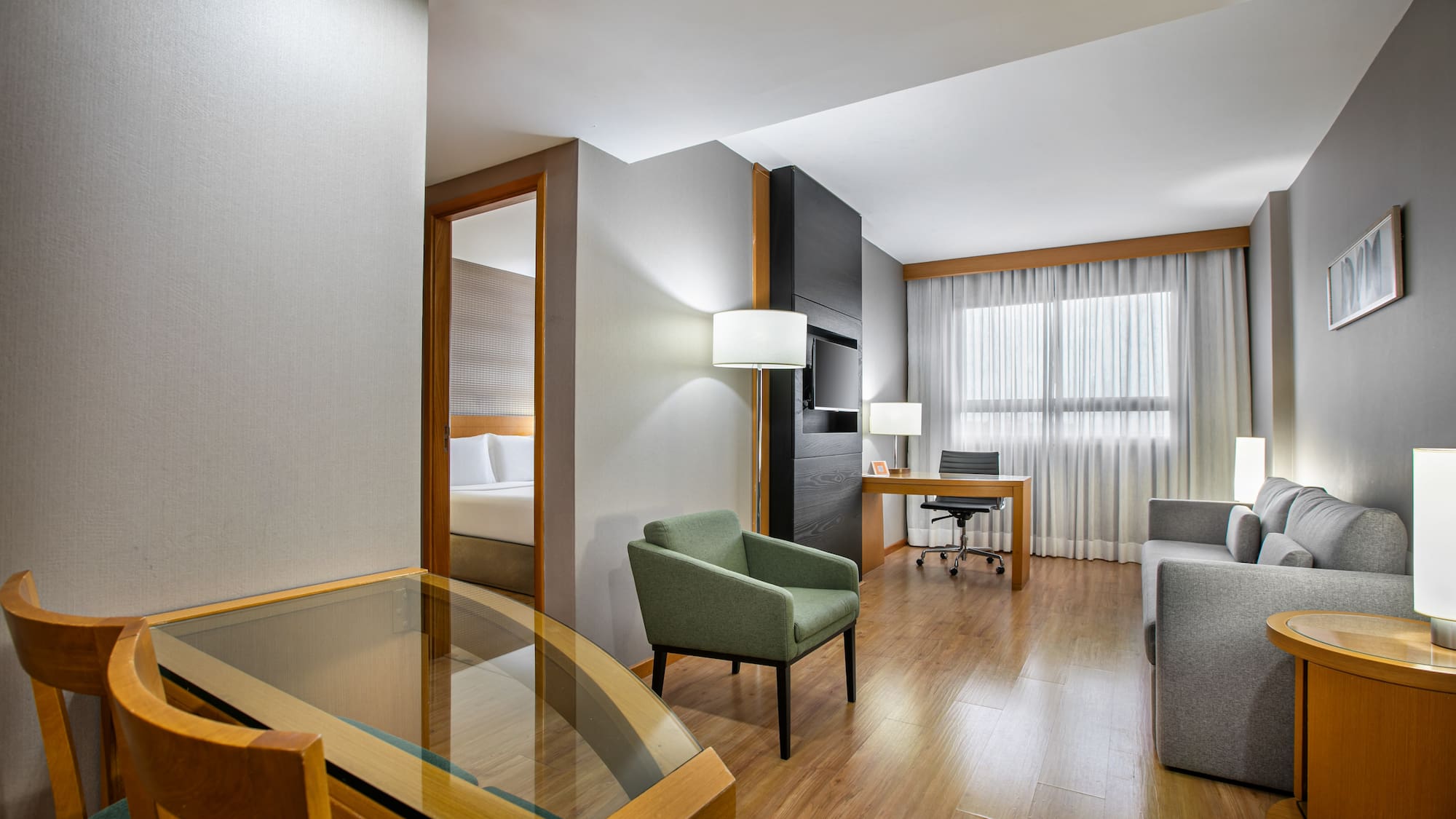 Contemporary hotel suite with separate living and sleeping areas.