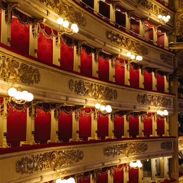 a red and gold theater with red curtains with Teatro alla Scala in the background
