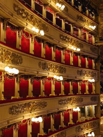 a red and gold theater with red curtains with Teatro alla Scala in the background