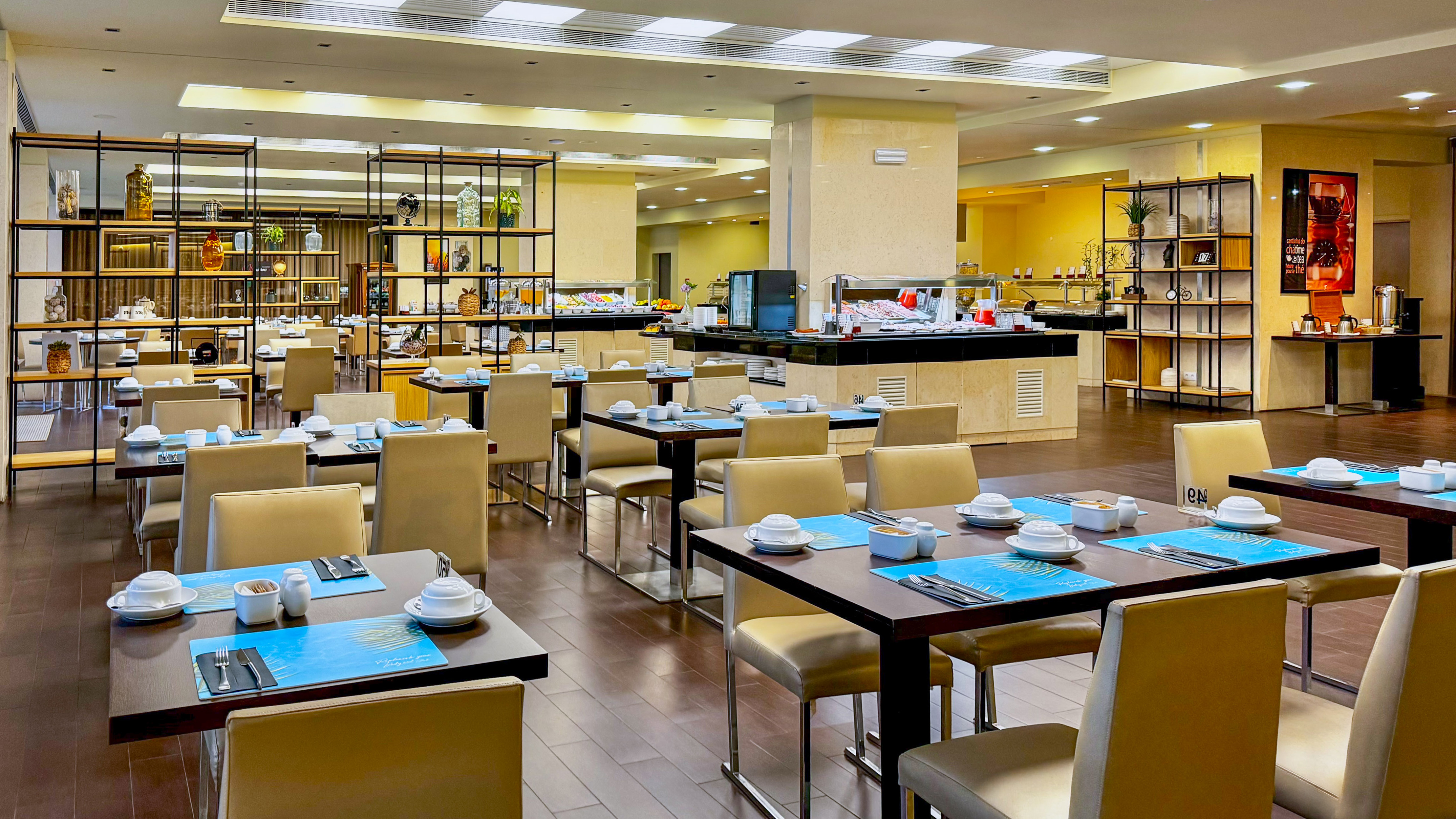 Spacious hotel buffet restaurant with set tables and food stations.