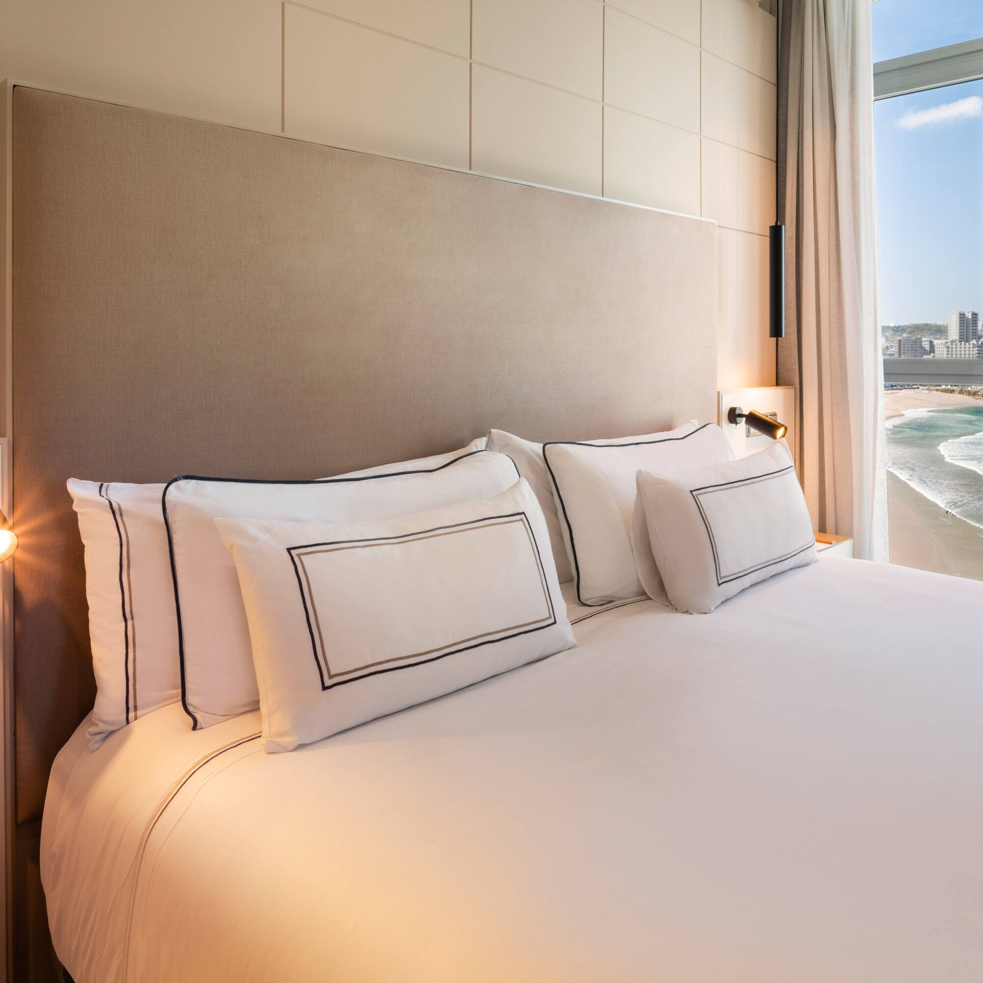 a bed with white sheets and pillows