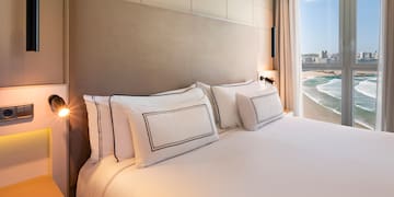 a bed with white sheets and pillows