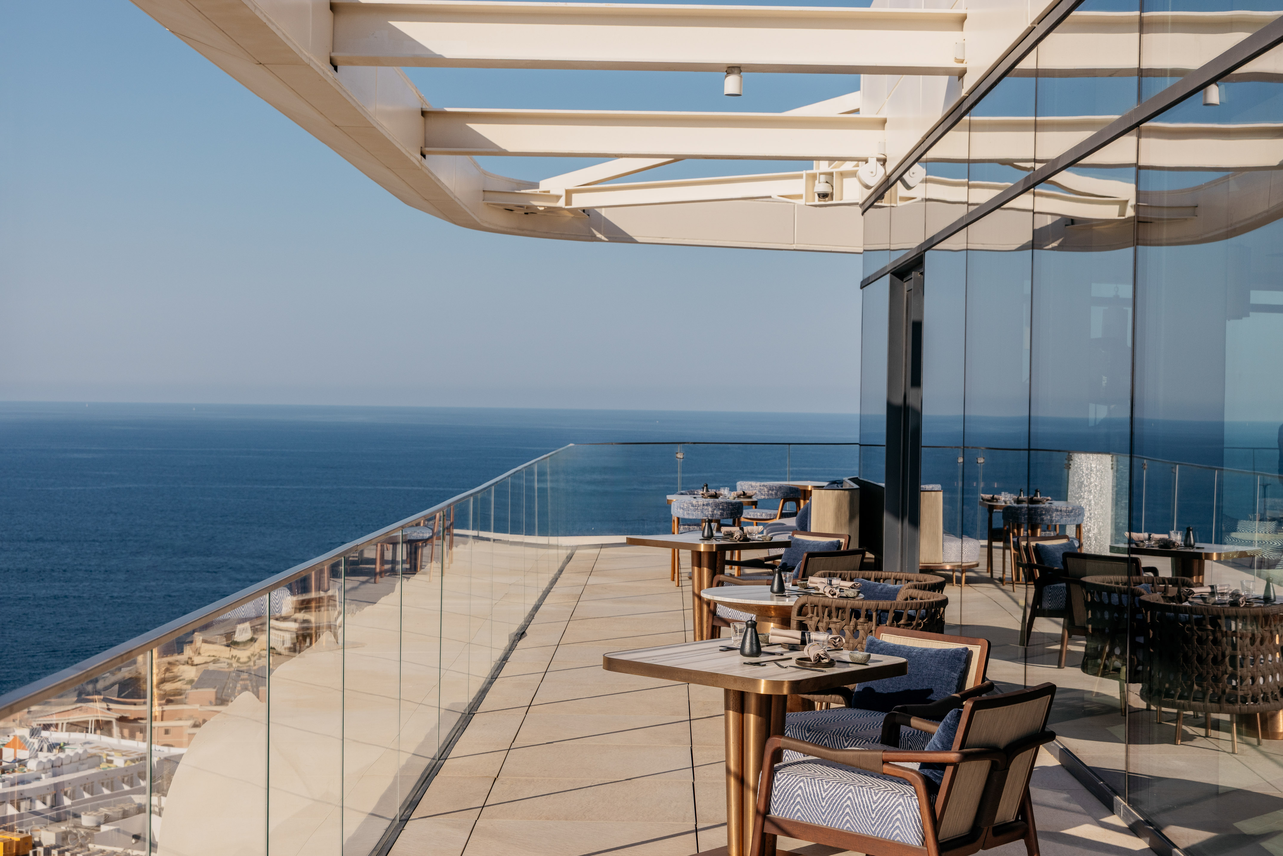 Oceanfront rooftop dining terrace with modern outdoor seating.