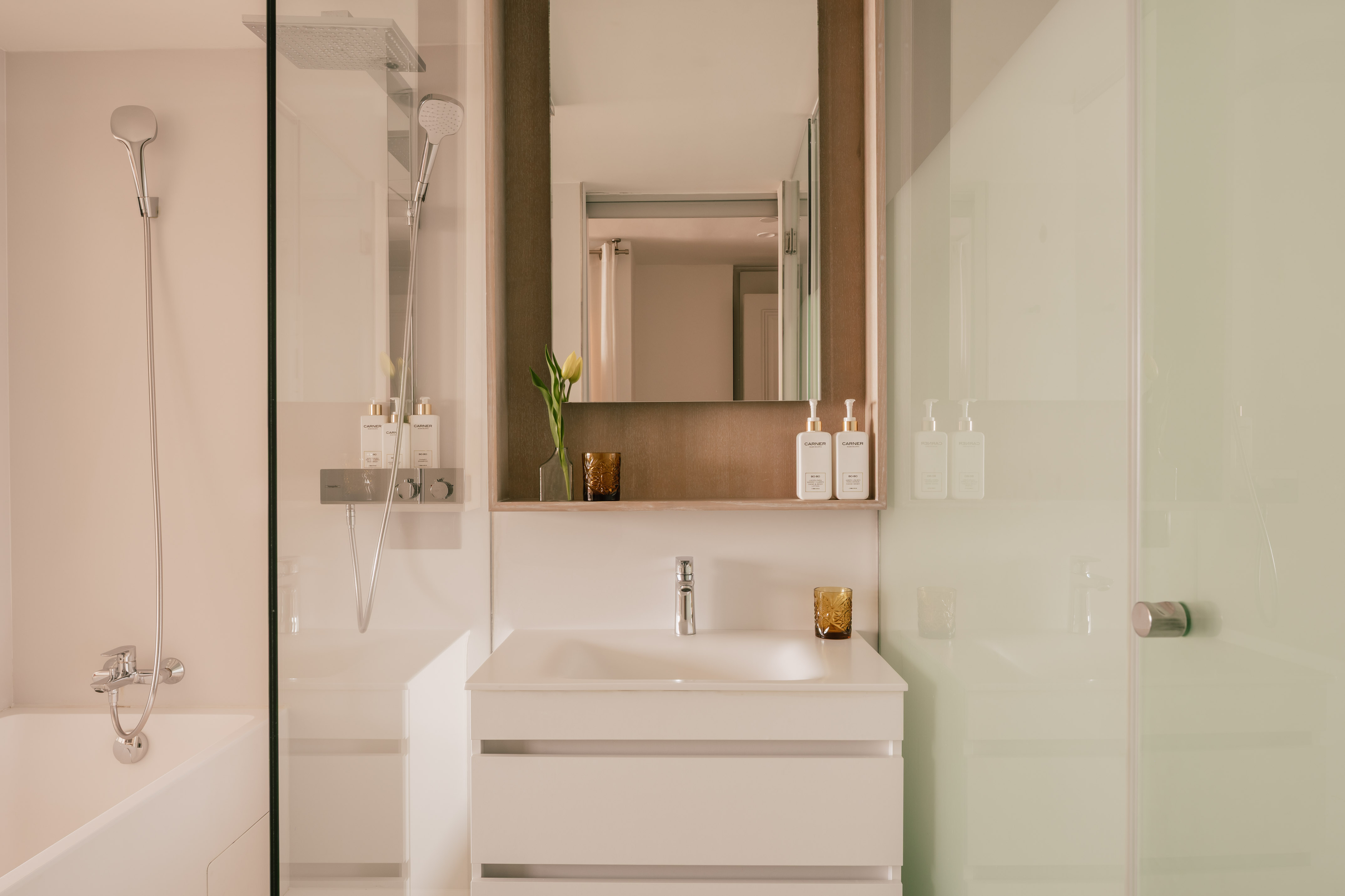Modern bathroom with glass shower, bathtub, and vanity sink.