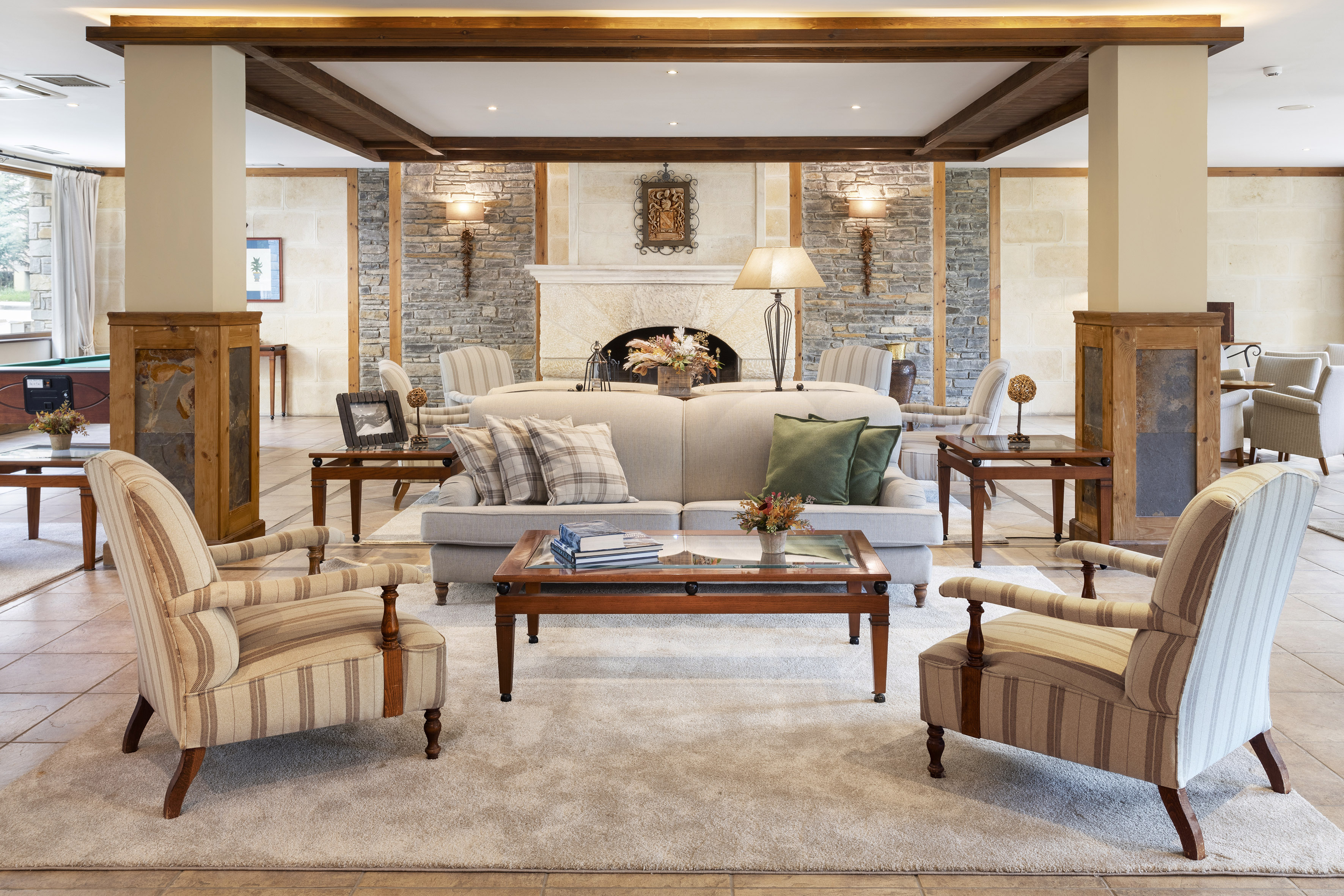 Cozy hotel lobby with stone fireplace, comfortable seating, and wooden beams.