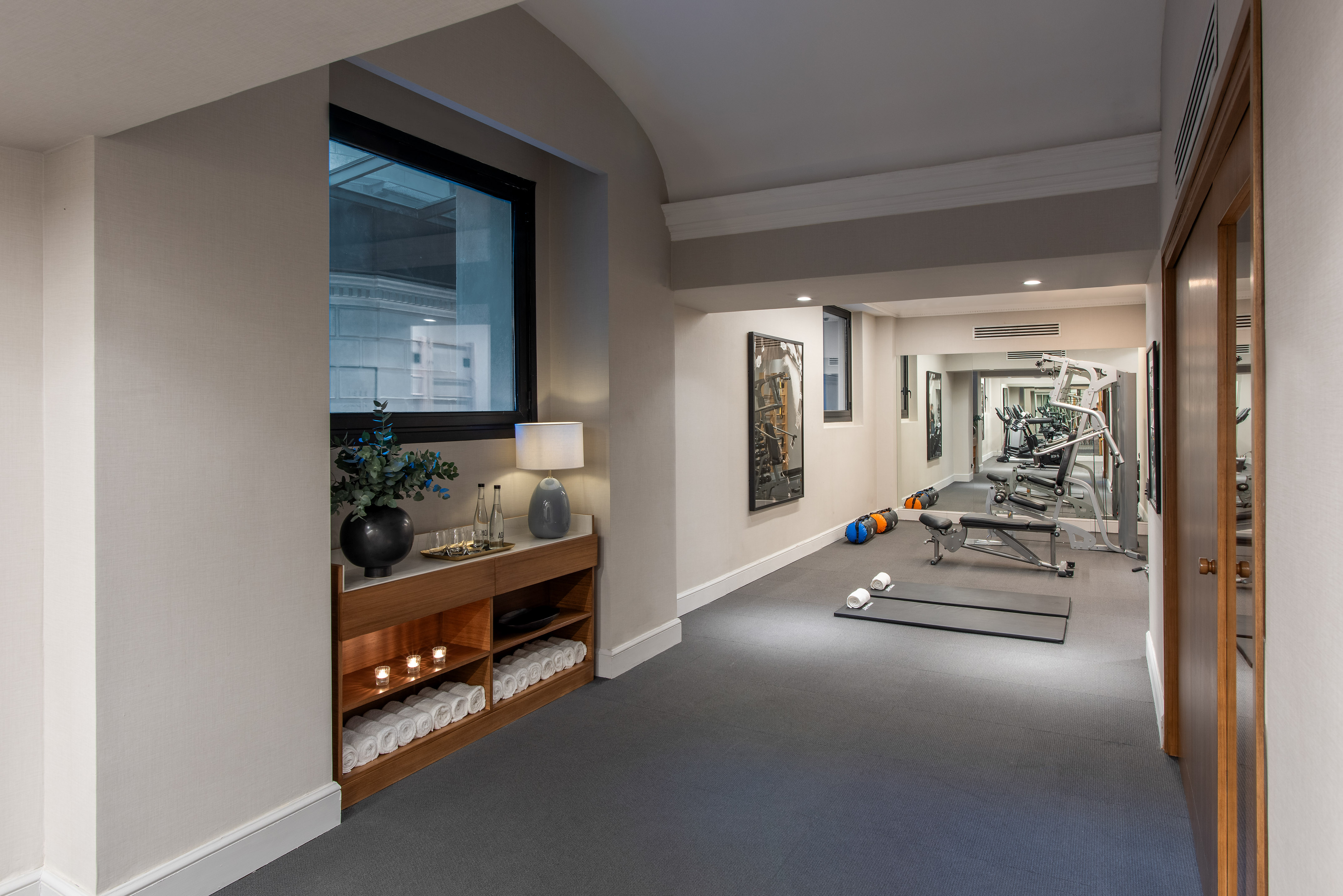 Hotel gym with workout equipment, yoga mats, fresh towels, and water bottles.