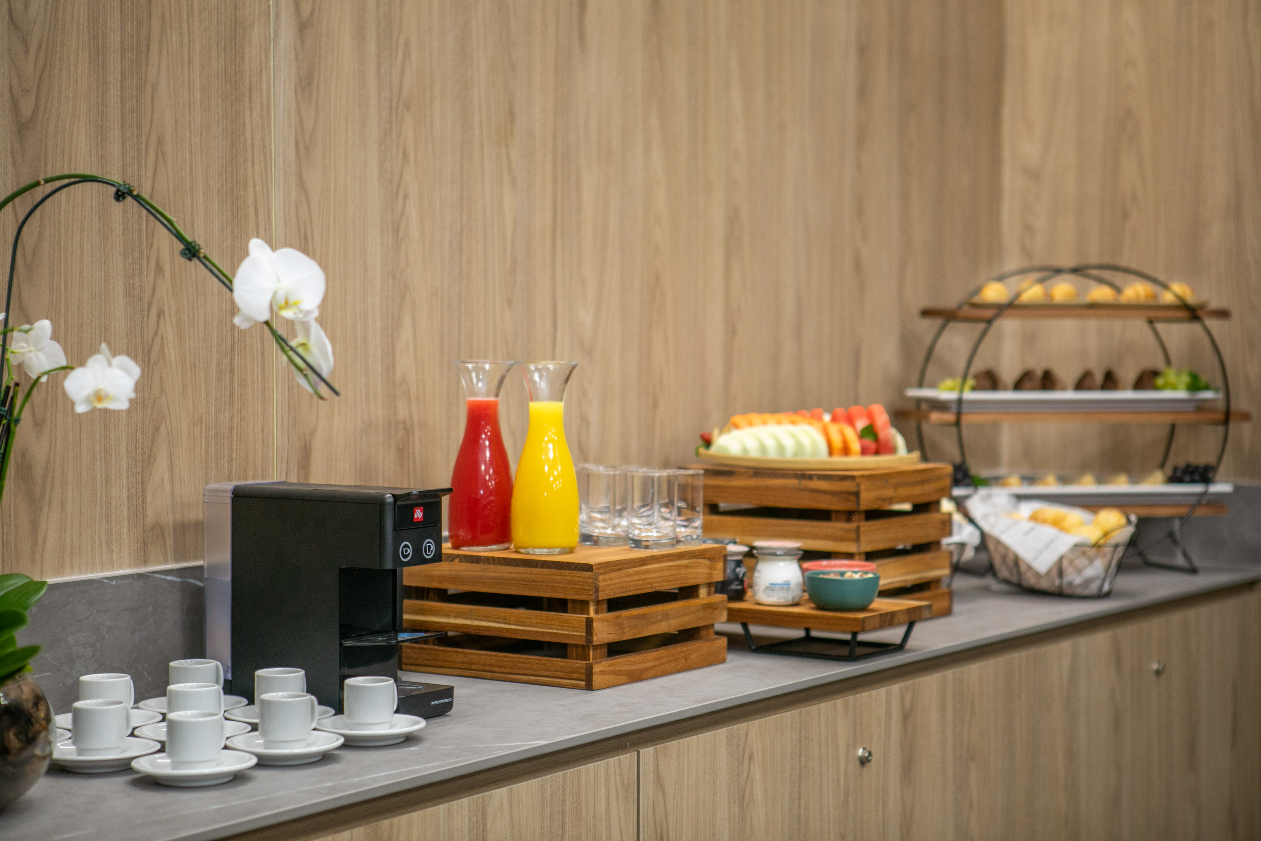 Hotel breakfast buffet with fresh fruit, juice, coffee station, and pastries.