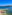 Malta: Bahía azul con pueblo costero, muelle y playa rocosa con bote.