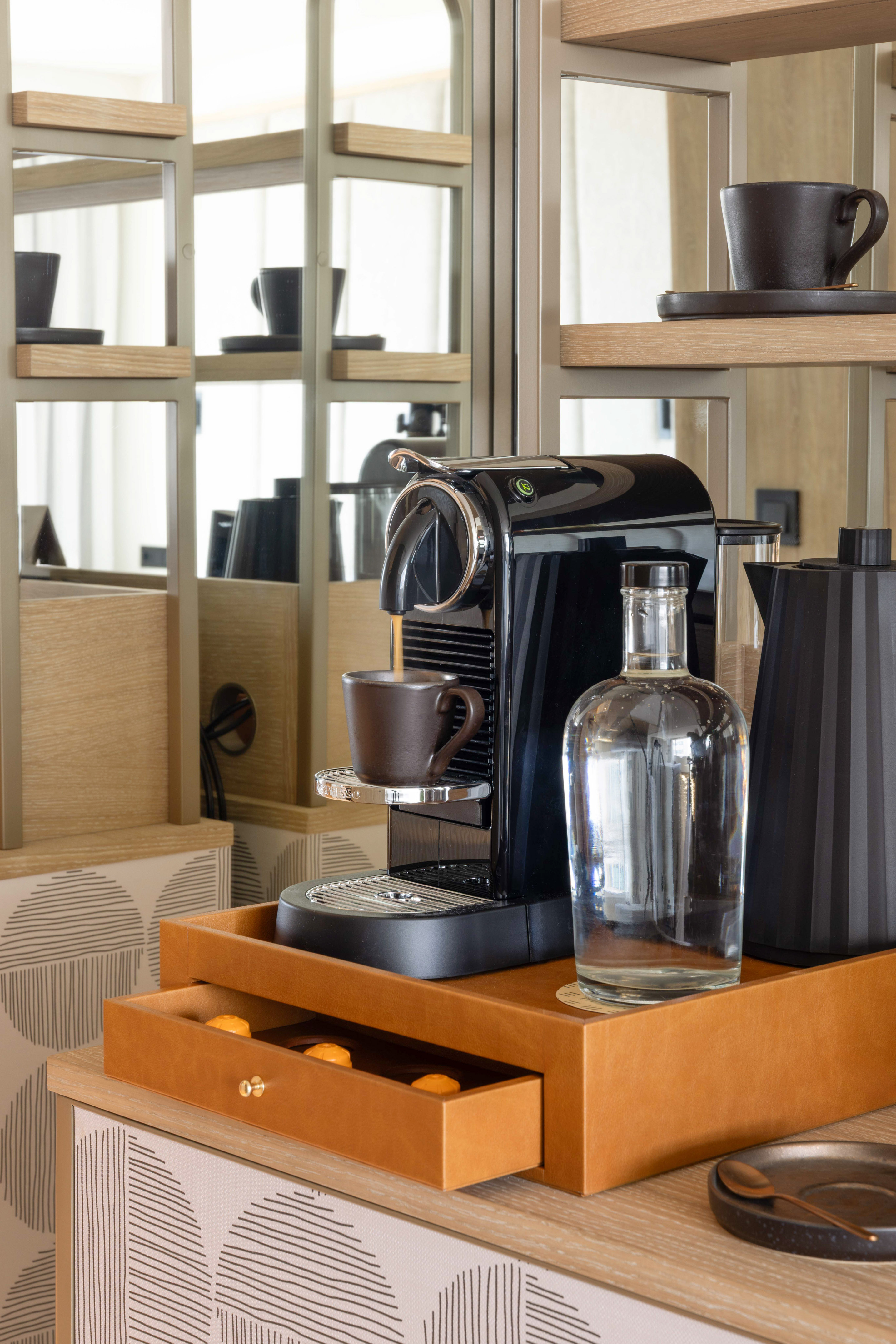 Modern Nespresso machine and kettle on hotel amenity tray with coffee pods.