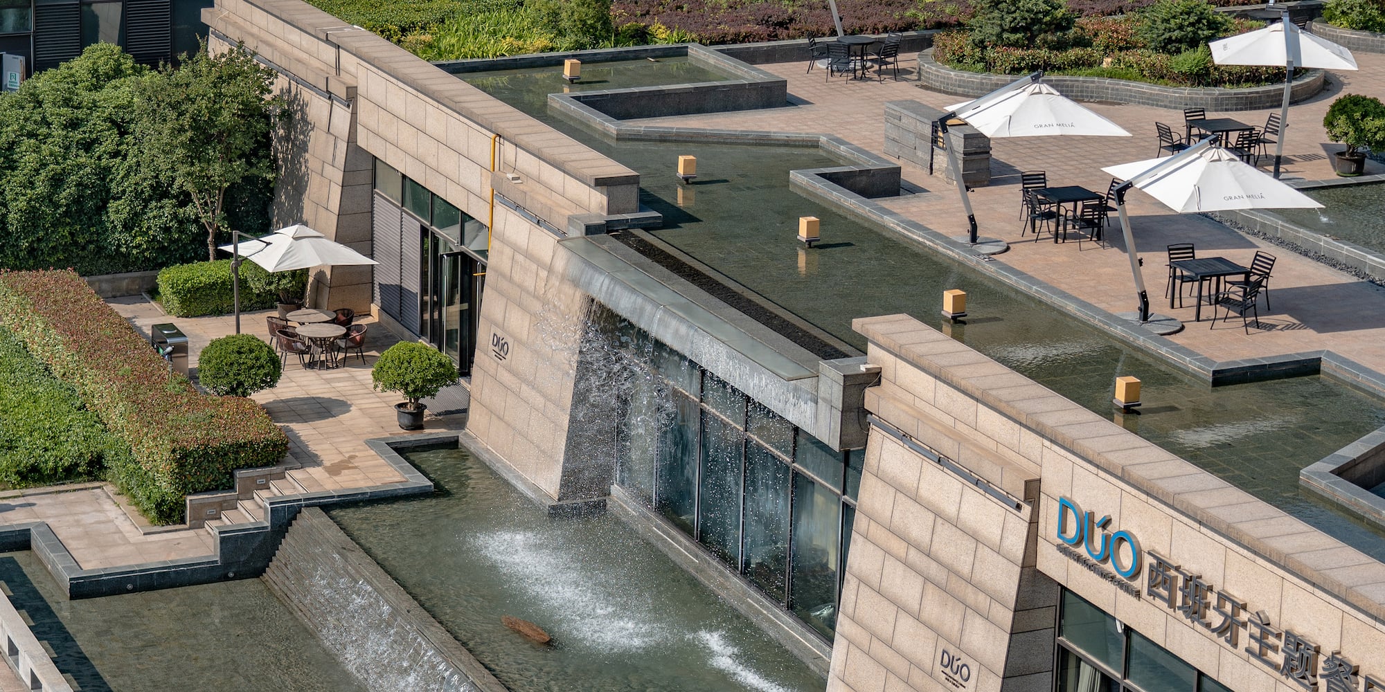 a building with a fountain and umbrellas