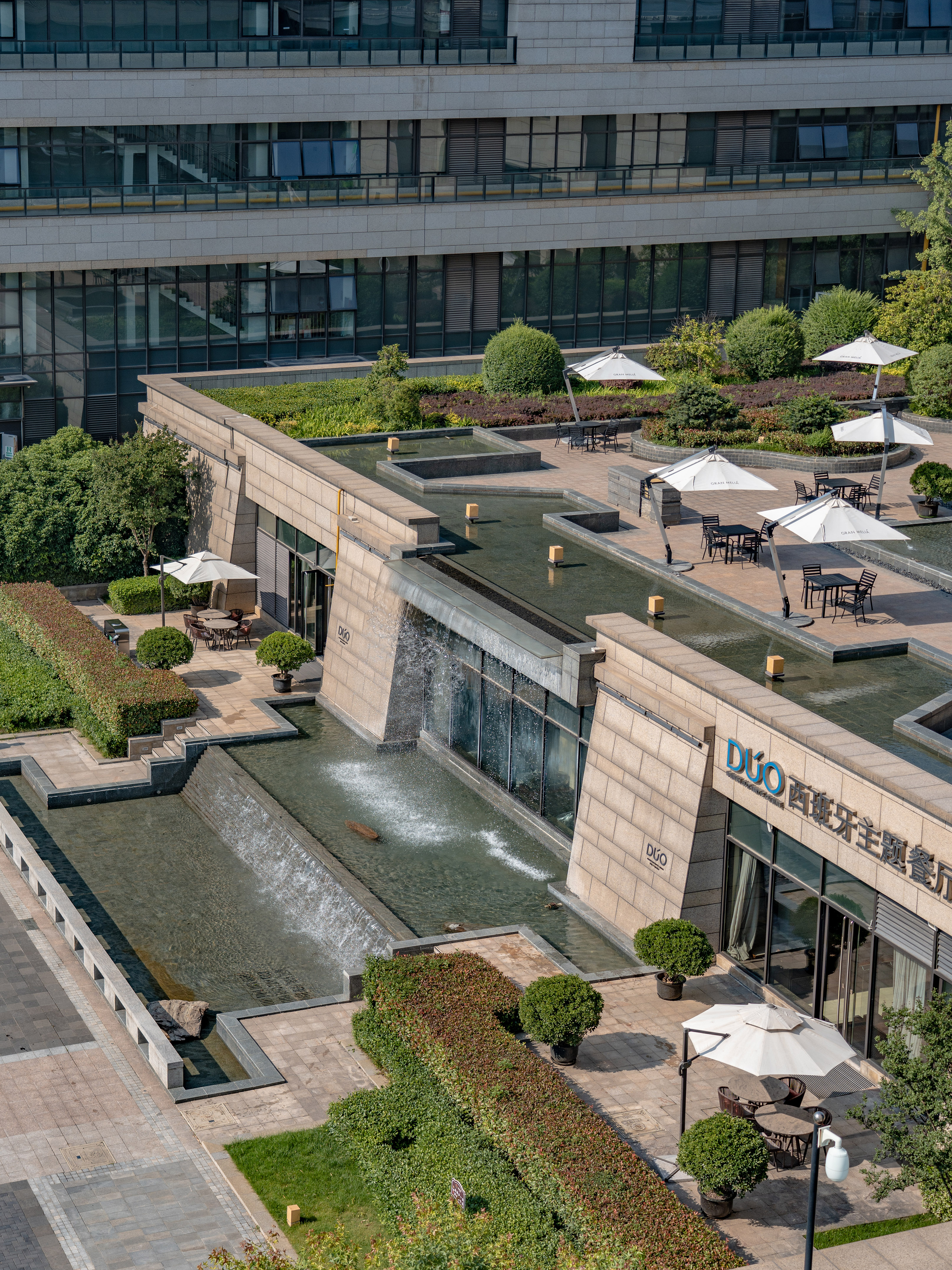 DUO restaurant patio with water features, outdoor seating, and lush landscaping.