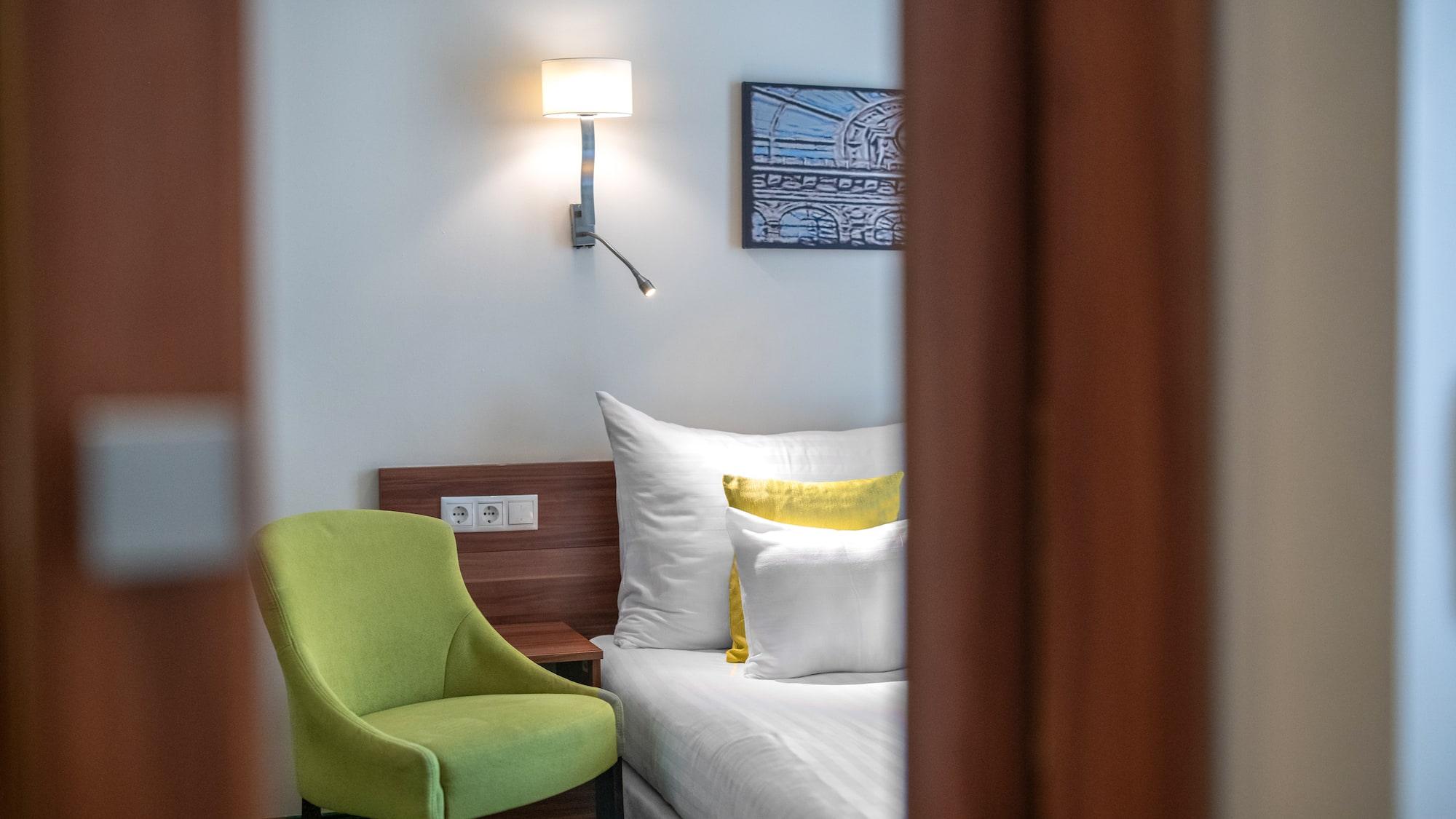 a green chair next to a bed