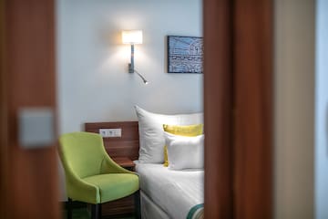 a green chair next to a bed