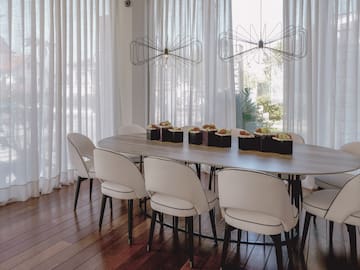 a table with chairs in a room with white curtains