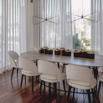 a table with chairs in a room with white curtains