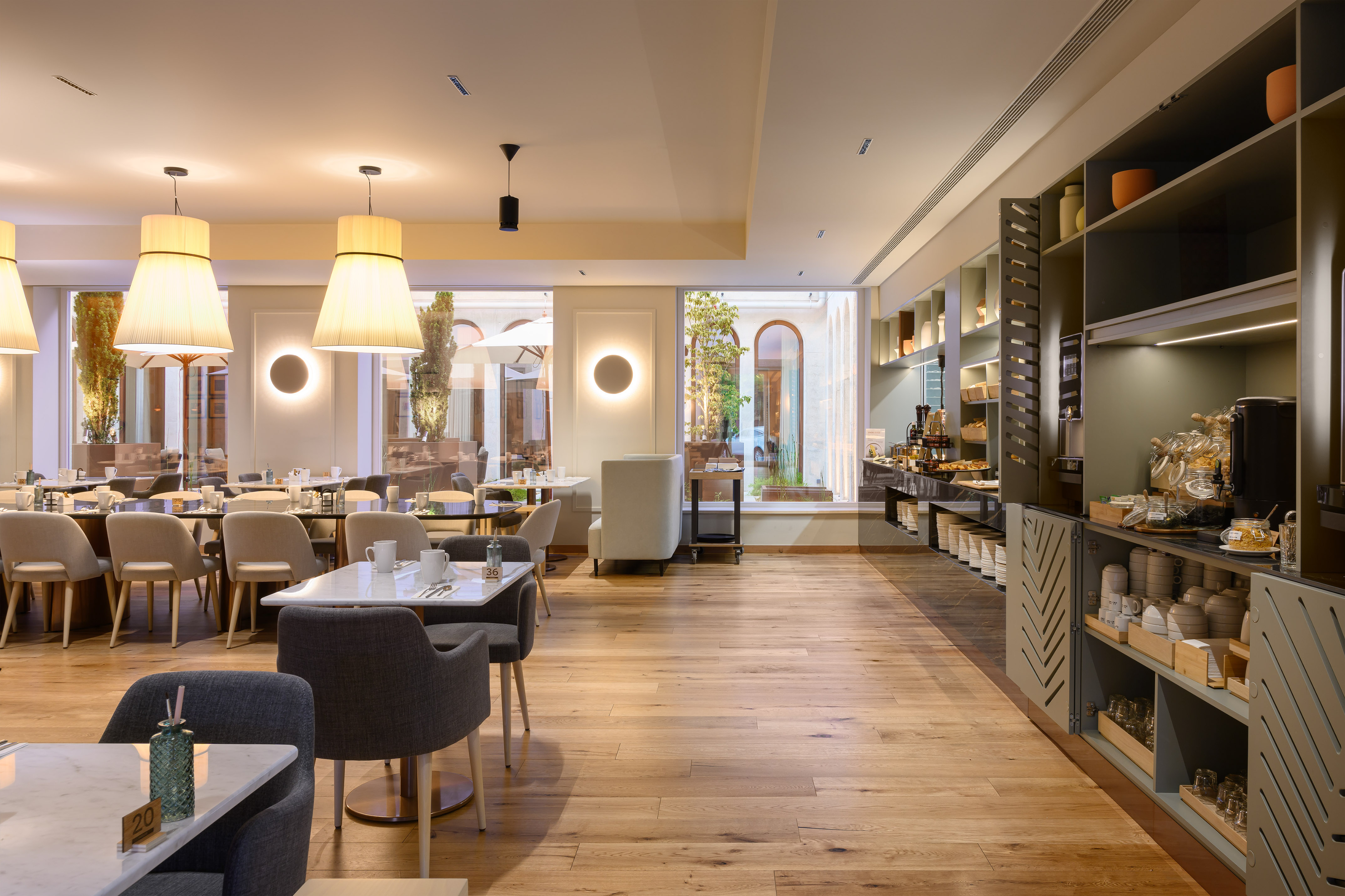 Modern restaurant with breakfast buffet, stylish seating, and courtyard view.