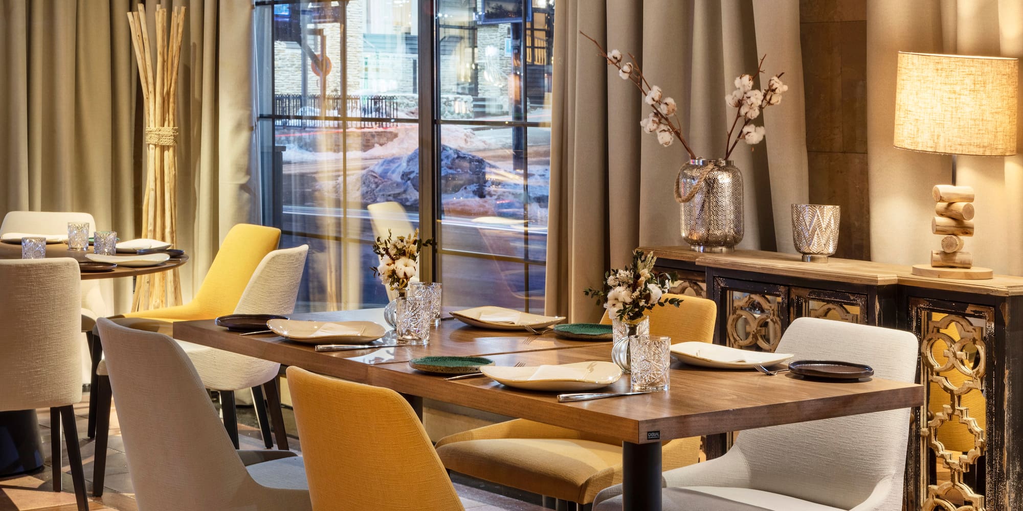 a table with chairs and vases in front of a window