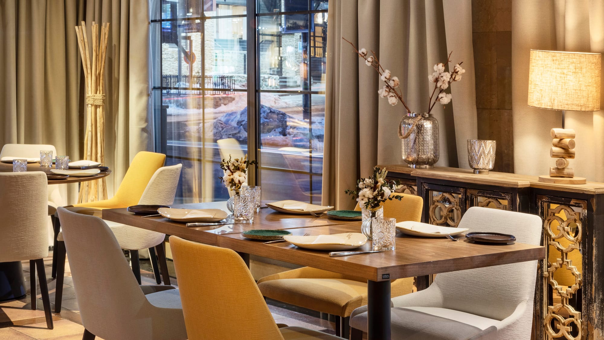 a table with chairs and vases in front of a window