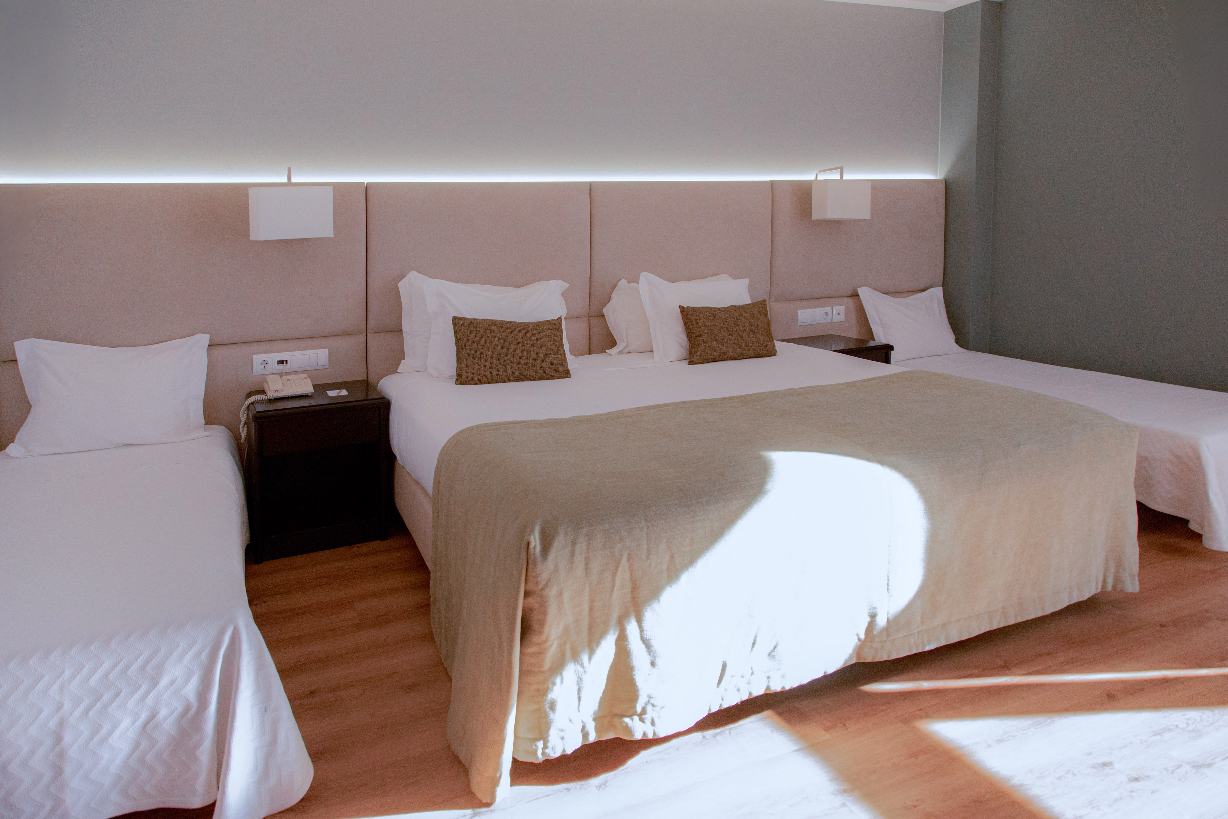 Spacious hotel triple room with double bed and two twin beds.